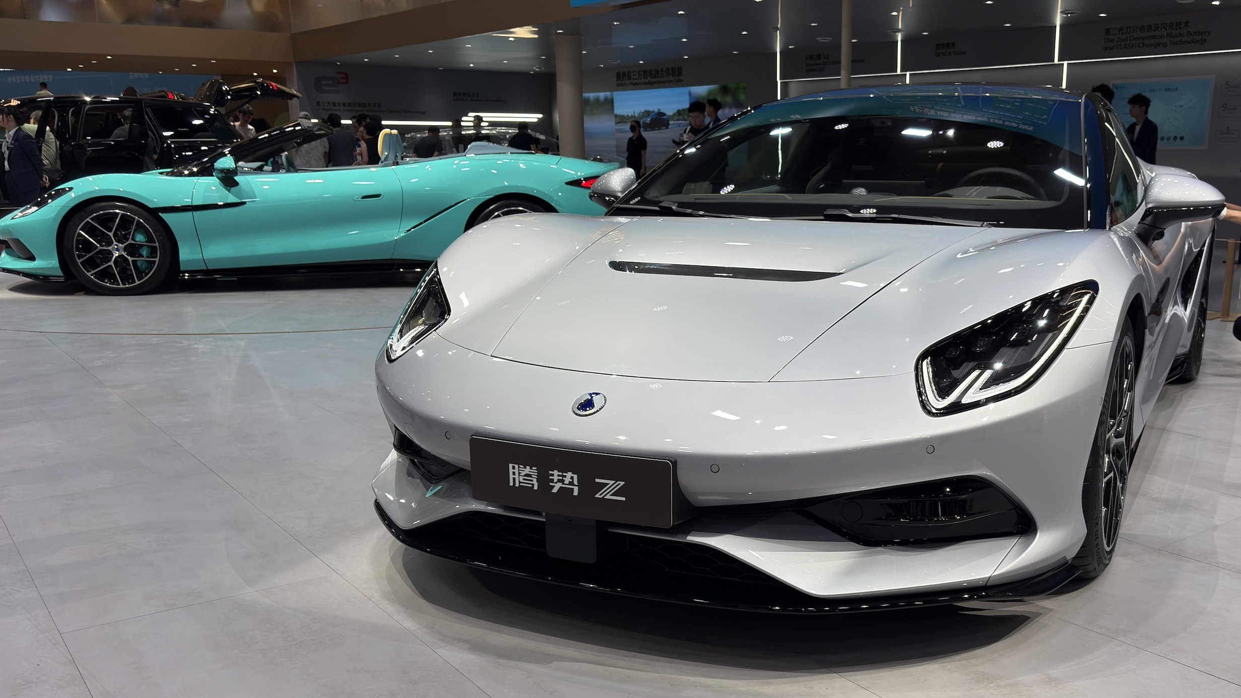 Silver Denza Z Coupe and teal Spider on the Chengdu show stand