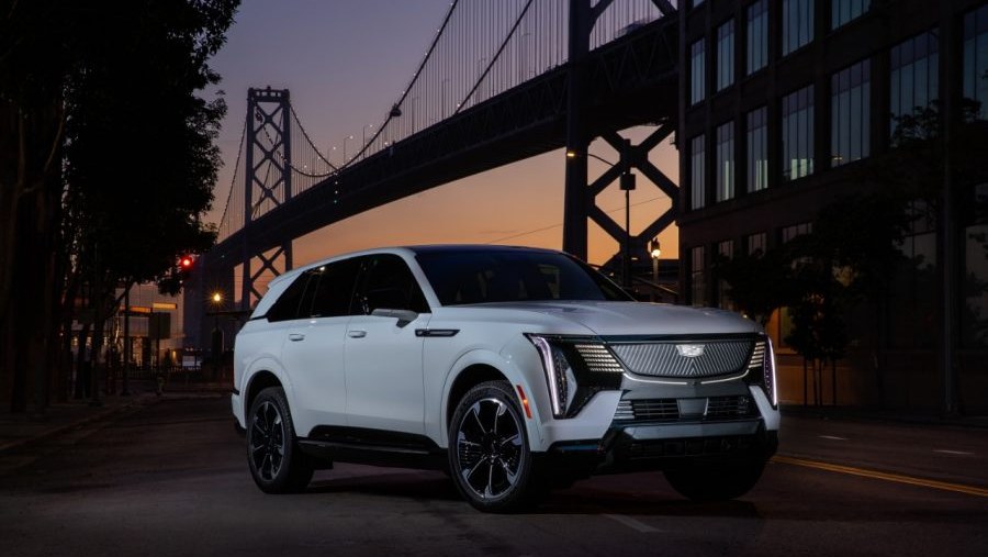 White Cadillac Escalade IQ parked at dusk near a suspension bridge