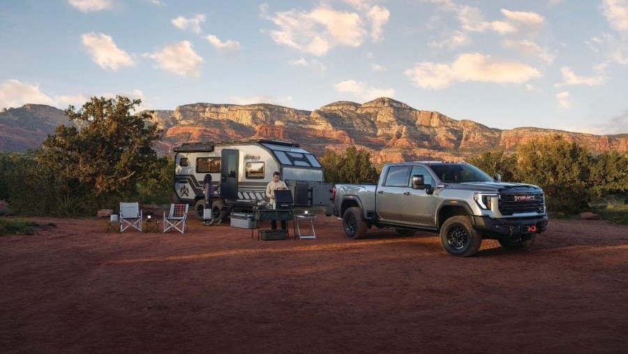 GMC Sierra AT4X parked at a desert campsite with a travel trailer