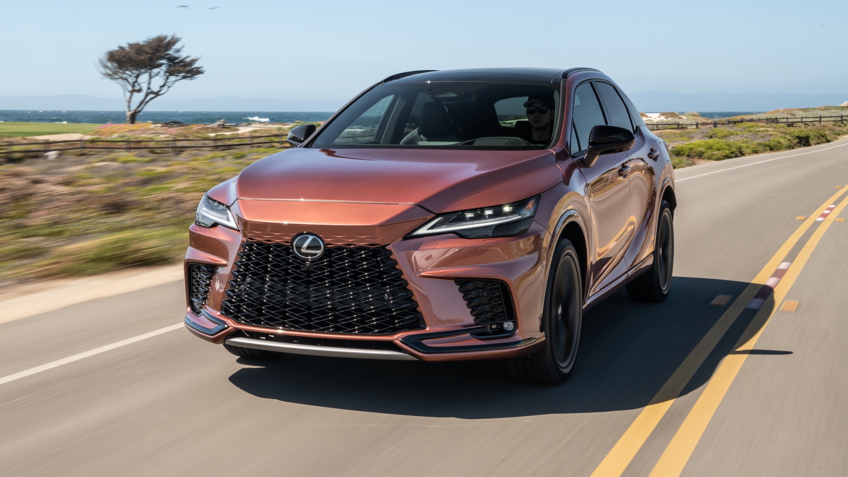 2026 Lexus RX 500h F Sport Performance in Copper Crest driving on a coastal road