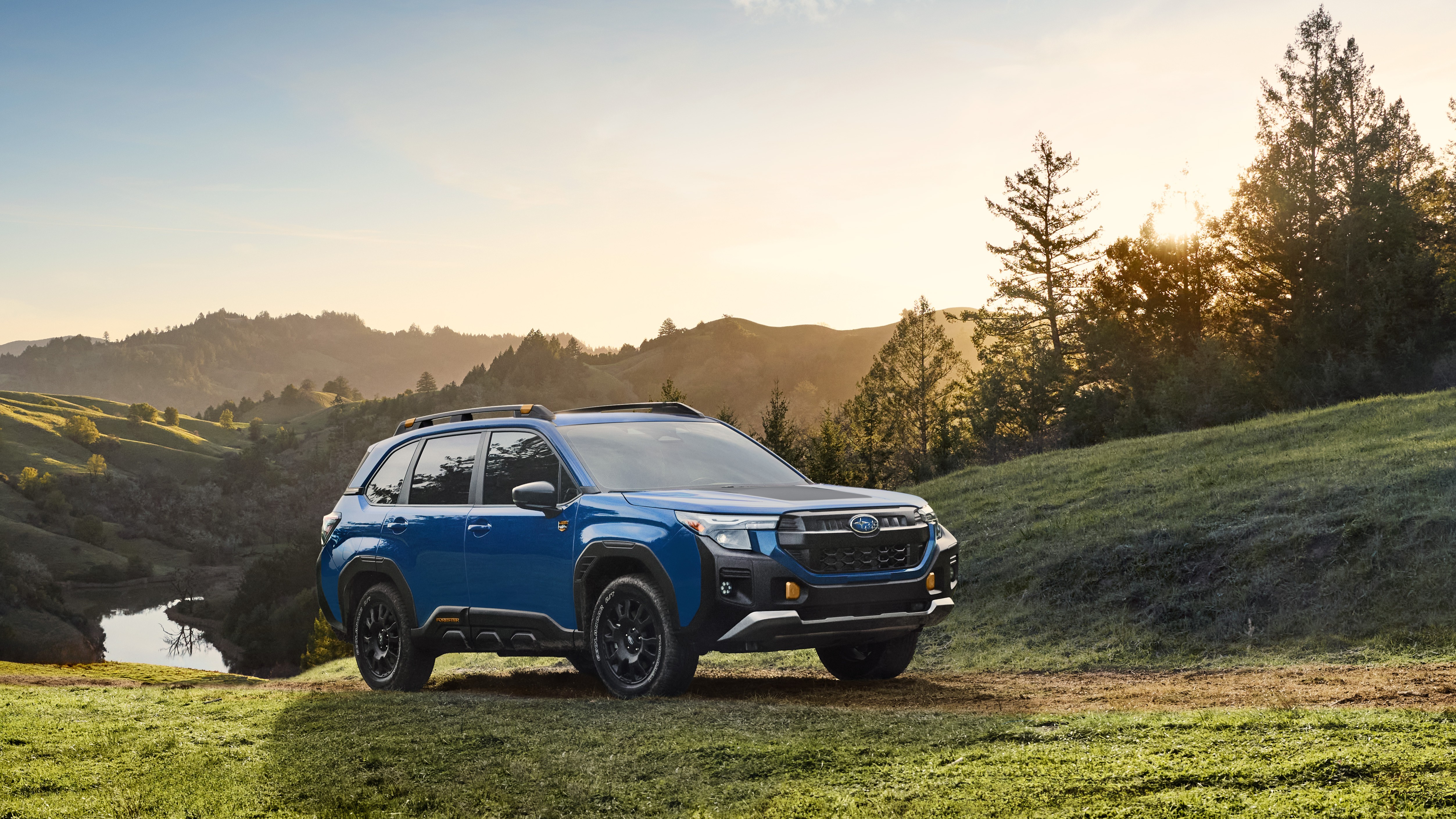 2027 Subaru Forester Wilderness Hybrid front three-quarter view on grassy hill