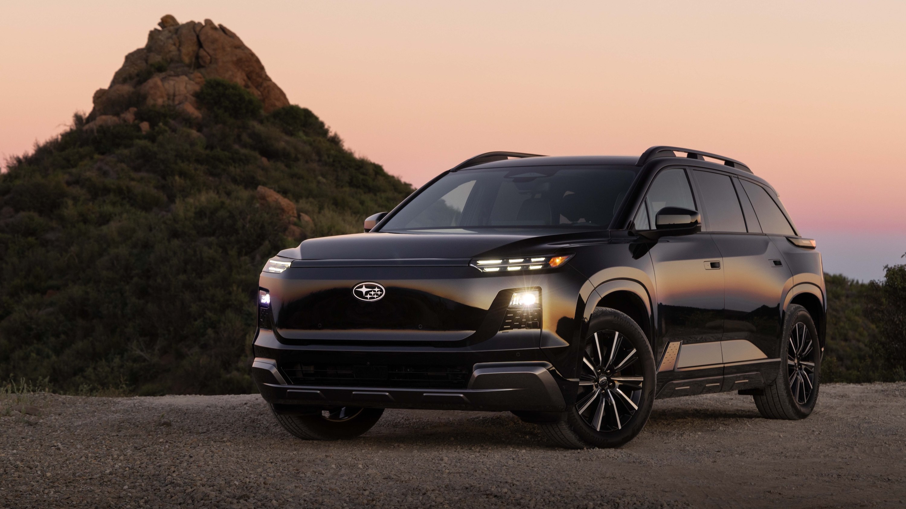 2028 Subaru Getaway electric SUV driving on a coastal highway at sunset