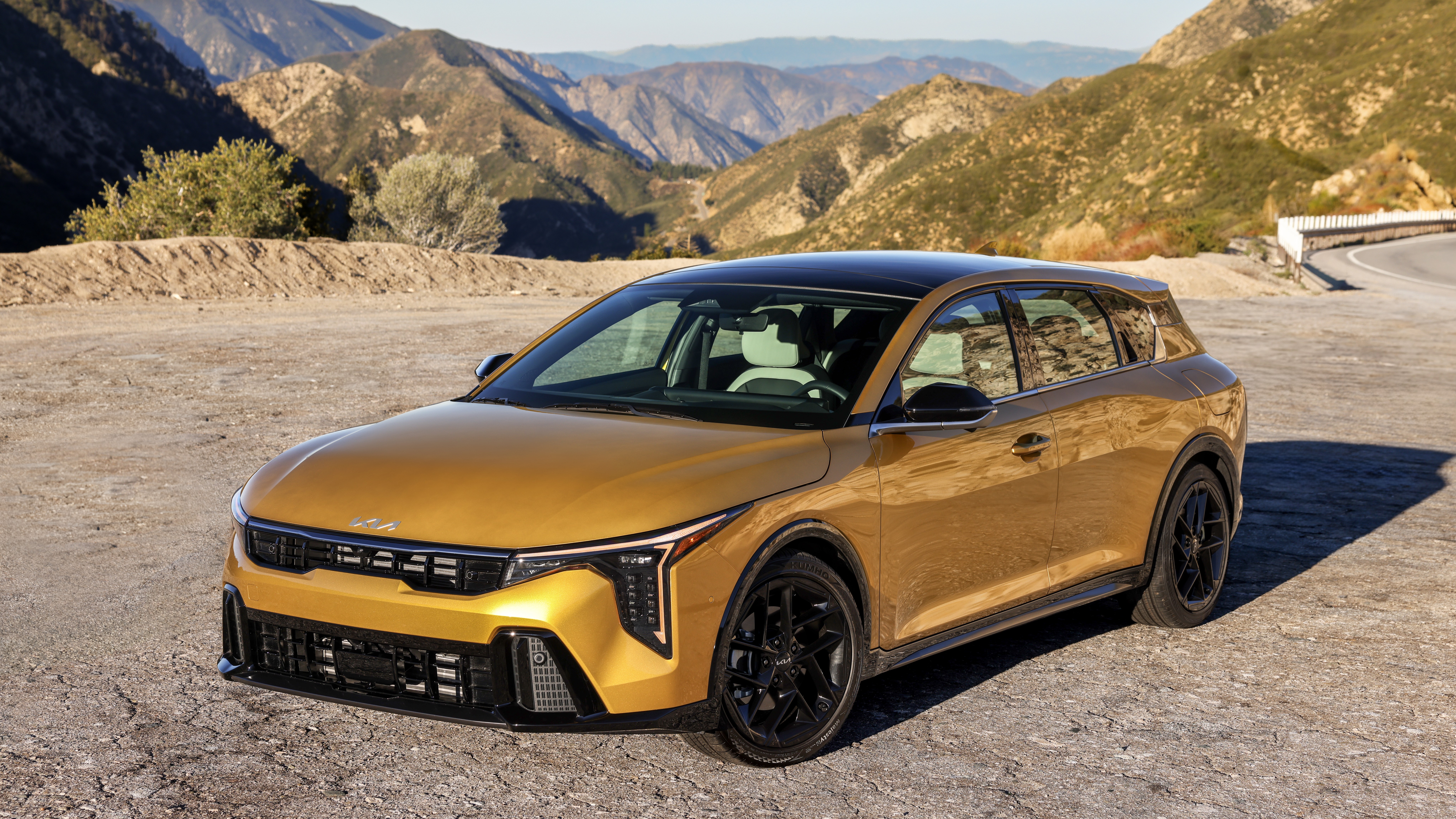 2026 Kia K4 hatchback front three-quarter view on a mountain road" — caption