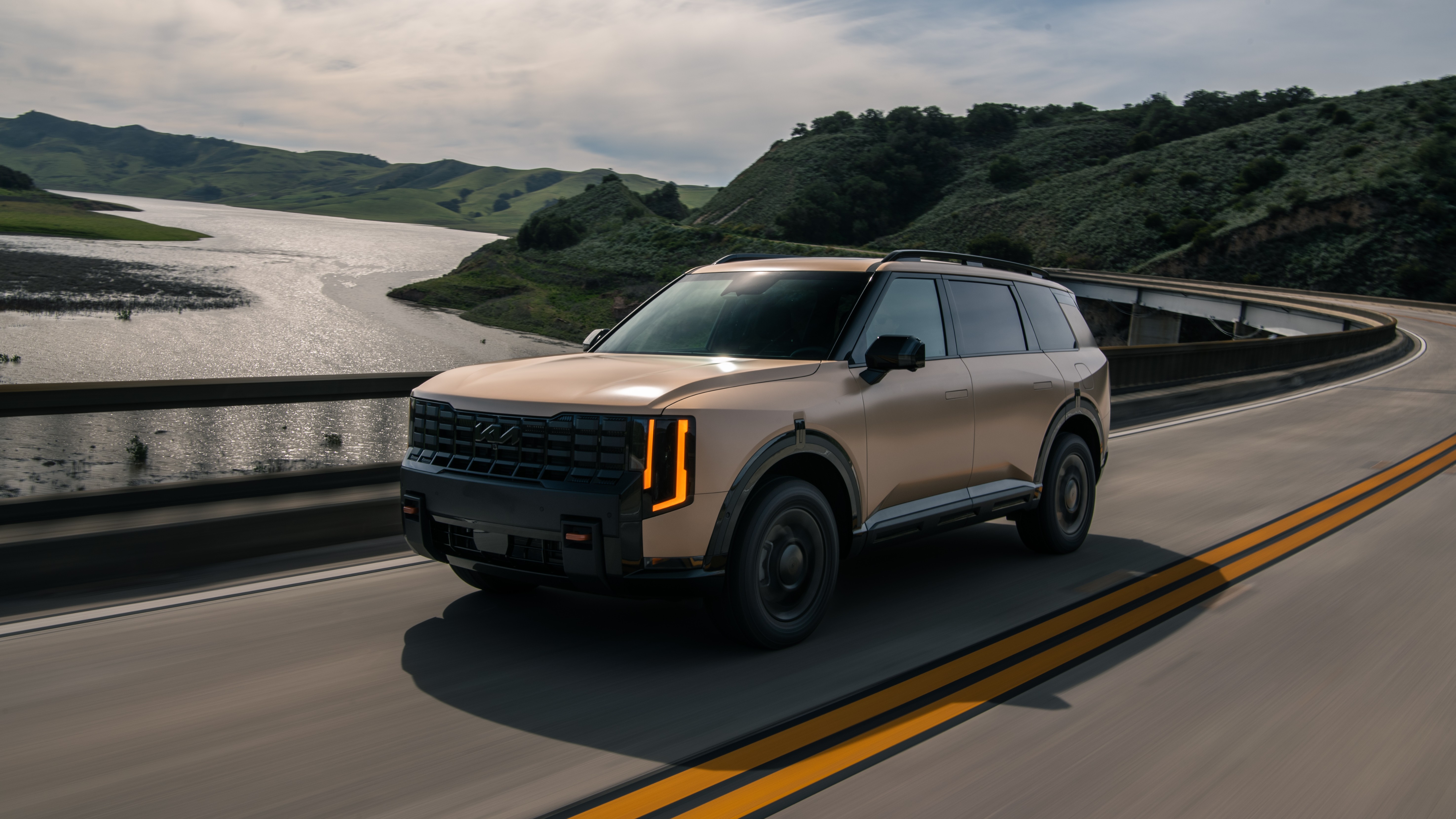 2027 Kia Telluride X-Pro driving across a bridge, front three-quarter view