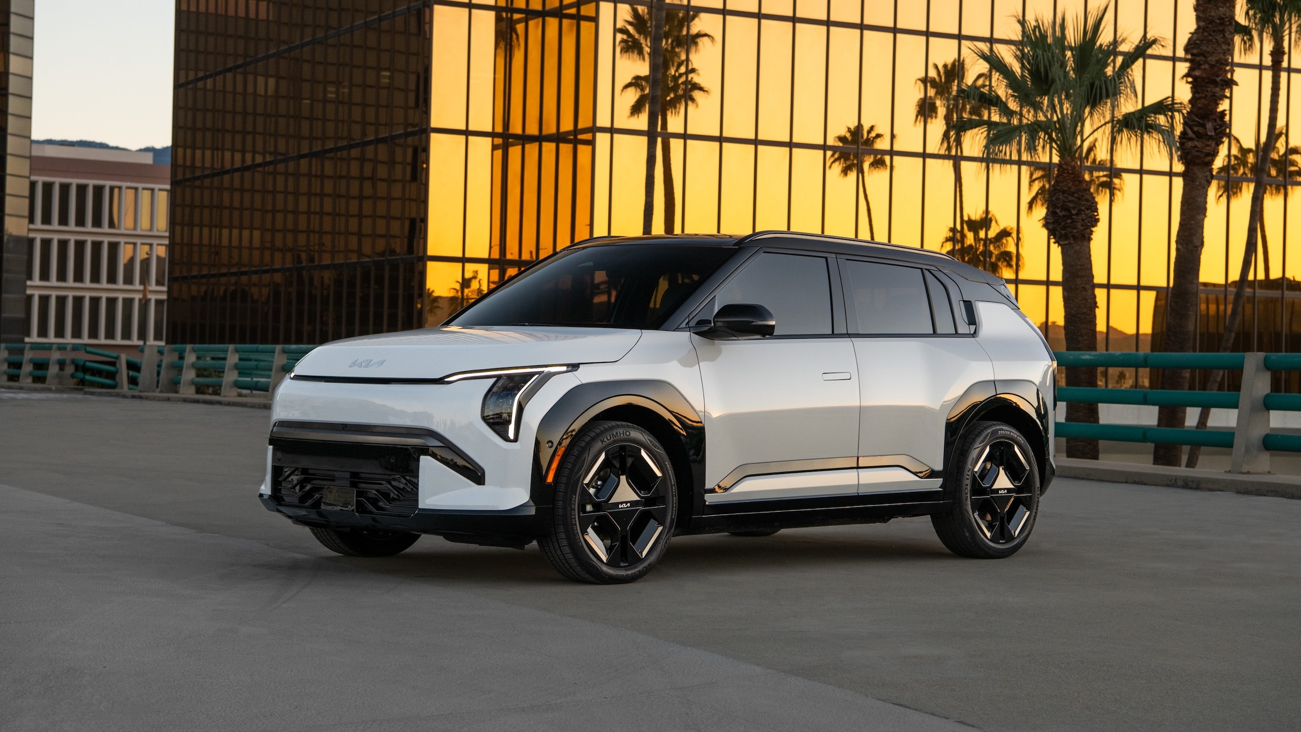 2027 Kia EV3 in white, front three-quarter view, parked by glass building