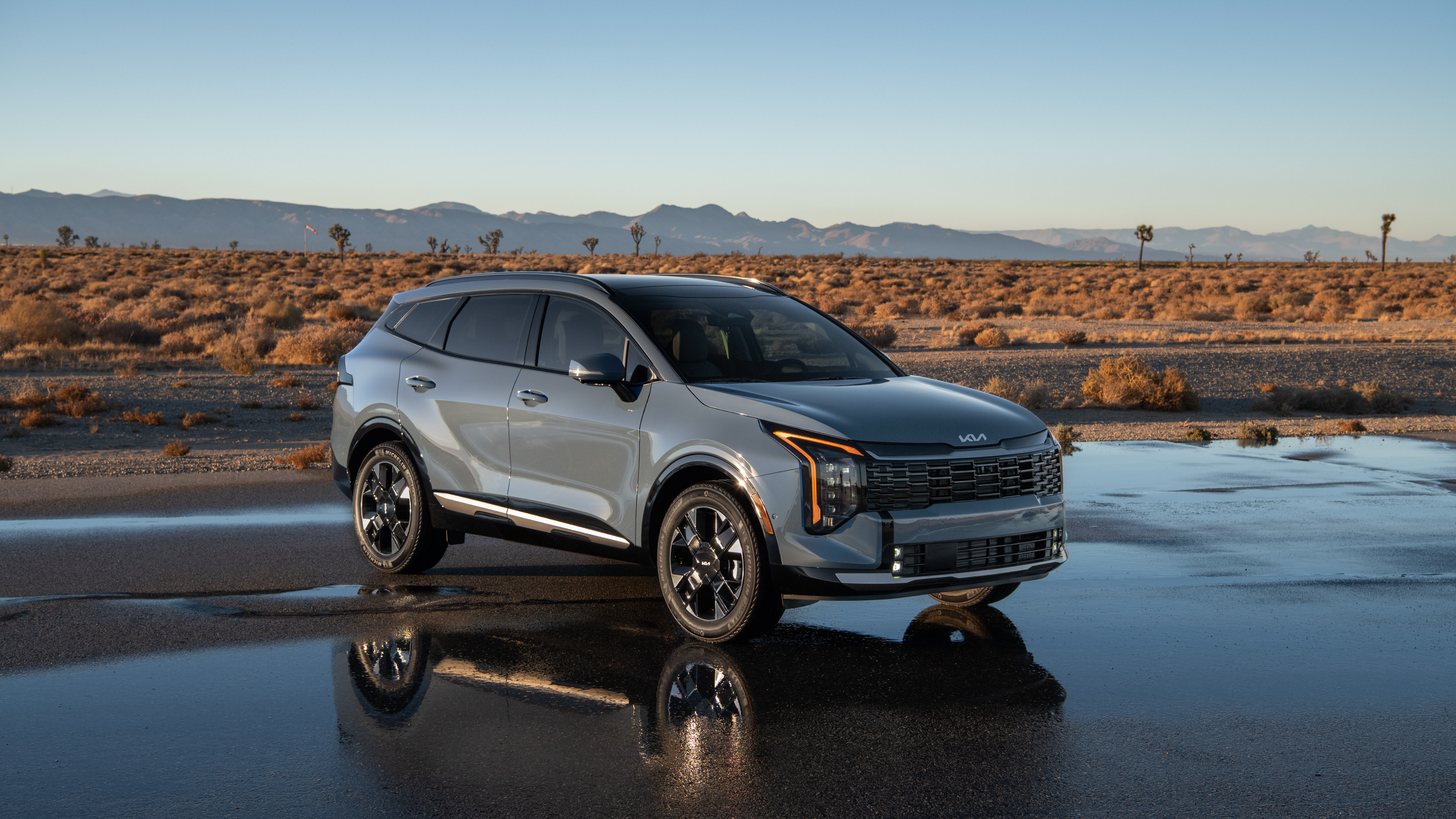 2027 Kia Sportage Hybrid parked on wet desert asphalt, front three-quarter view