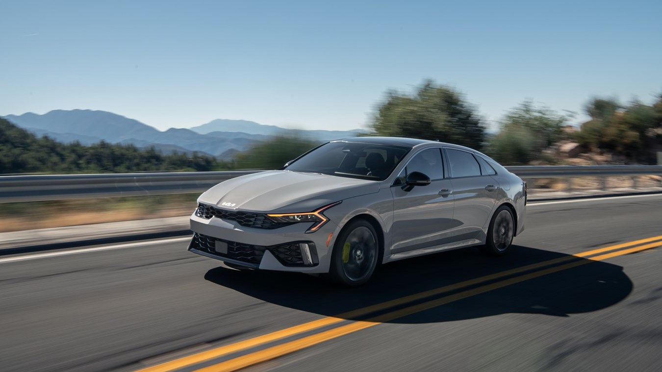 2027 Kia K5 driving on a mountain road, front three-quarter view