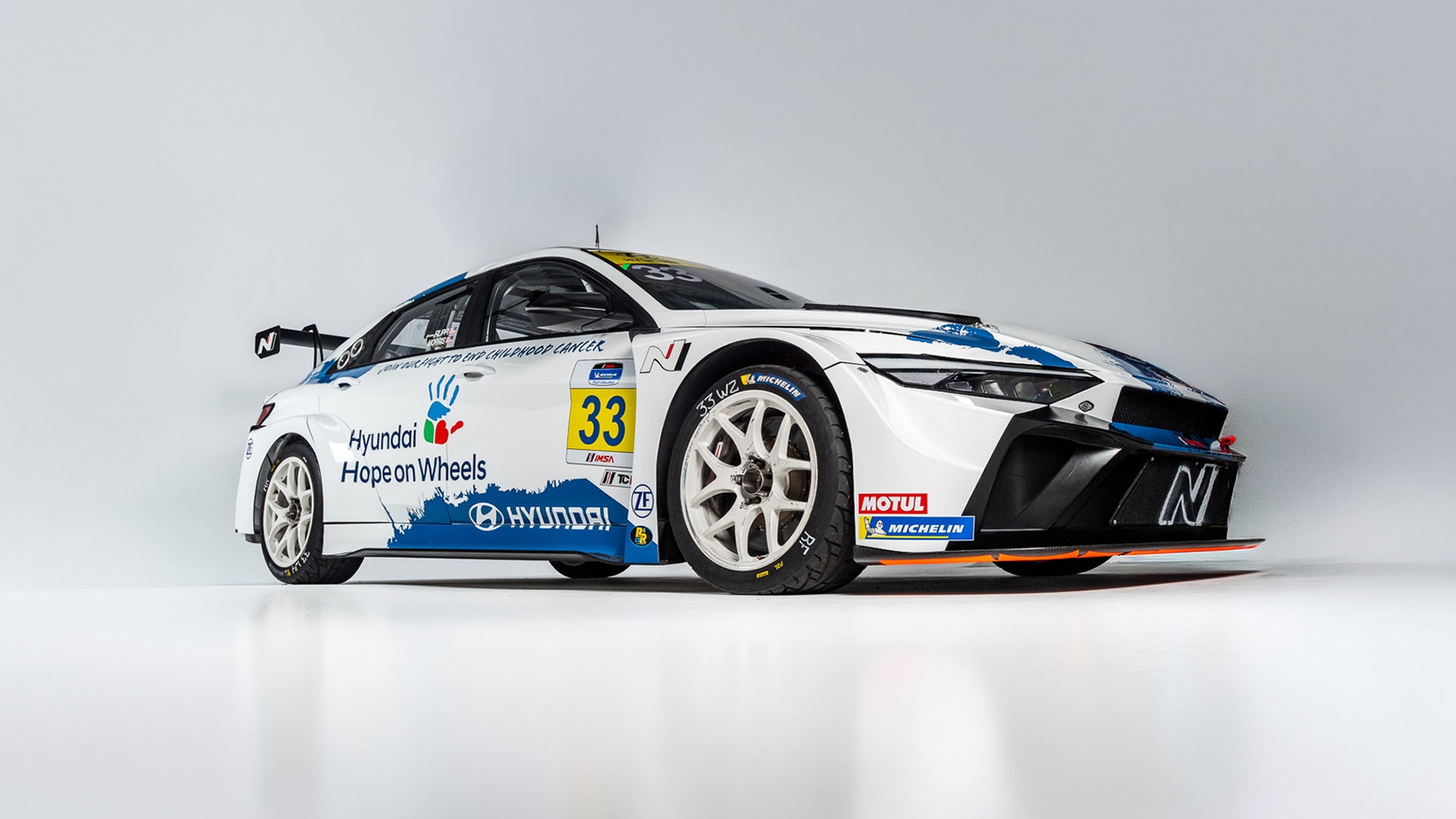 Hyundai Elantra N TCR with blue Hope on Wheels handprint livery, front three-quarter view