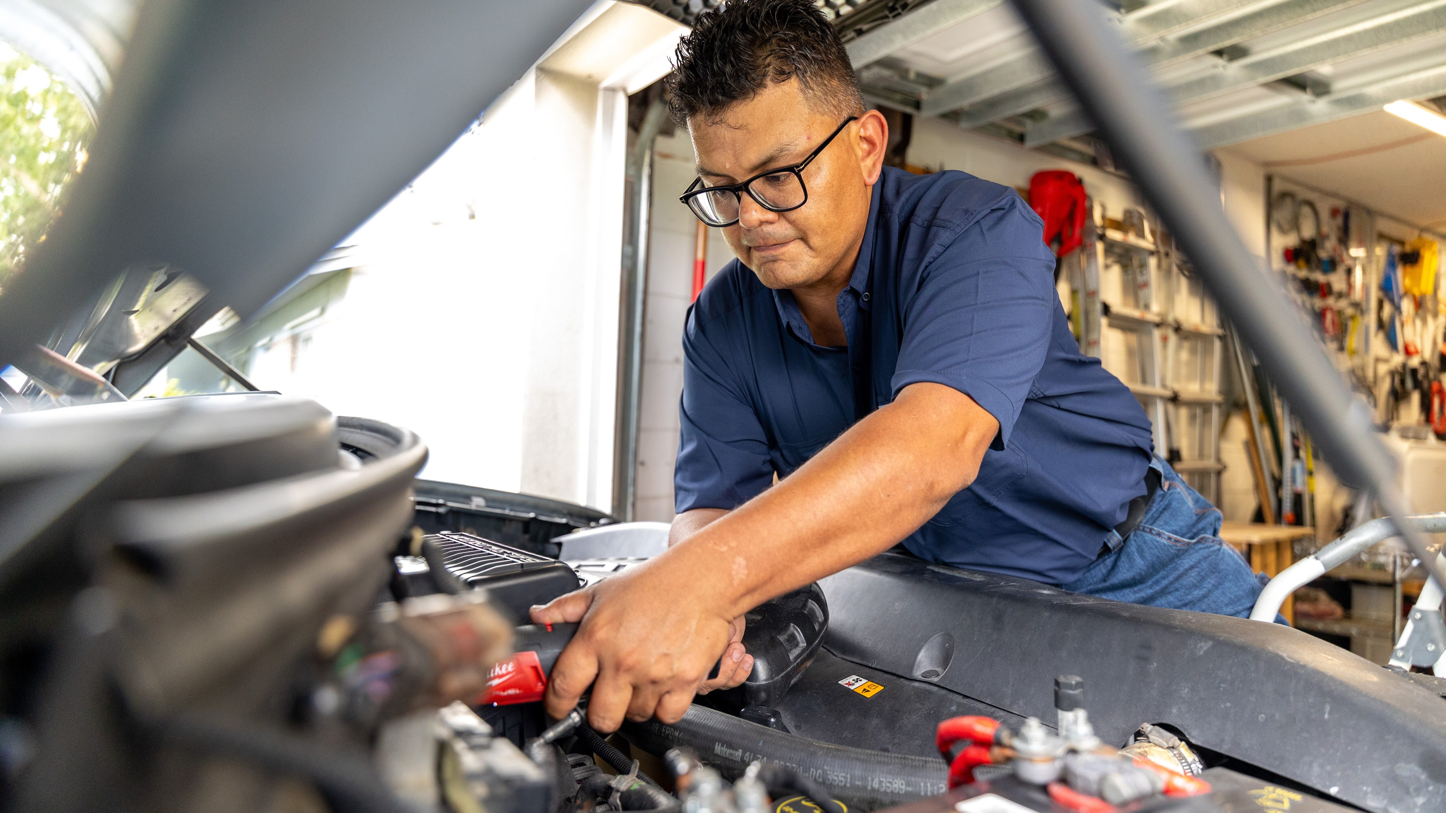 Technician uses a cordless ratchet under the hood of a pickup