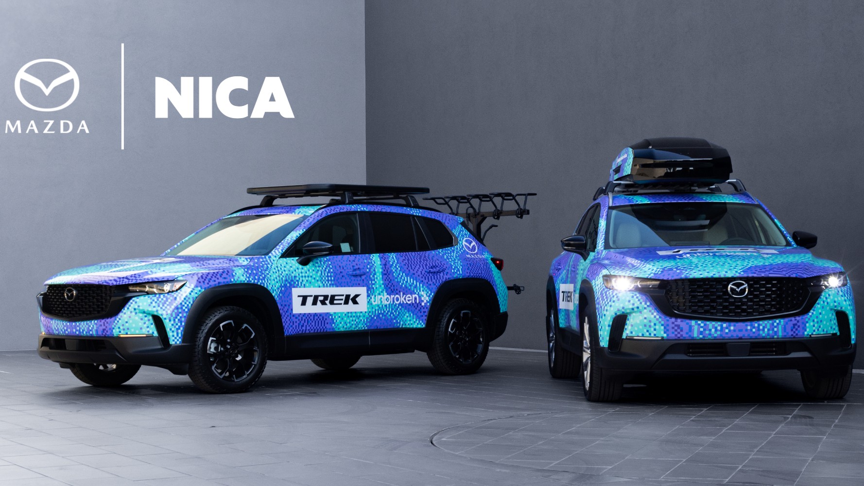 Two Mazda CX-50 SUVs in Trek race livery with bike racks and roof boxes