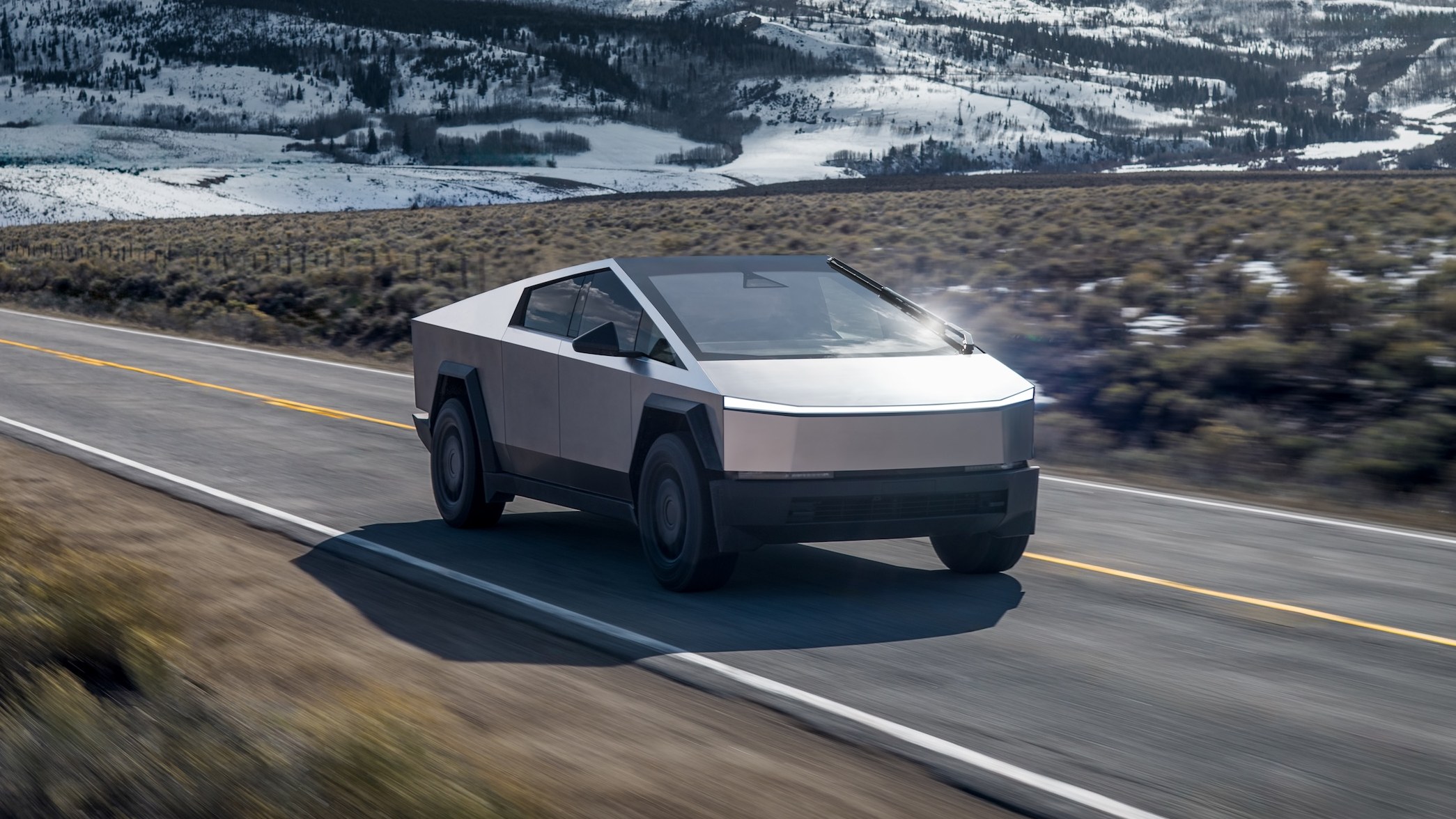 Tesla Cybertruck driving on a mountain highway in front three-quarter view