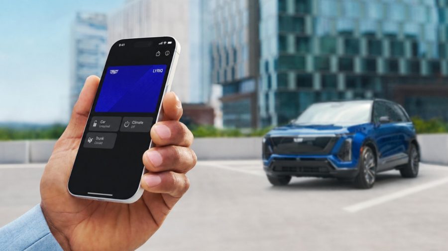 Hand holding an iPhone with a Cadillac digital key, blue Cadillac EV behind
