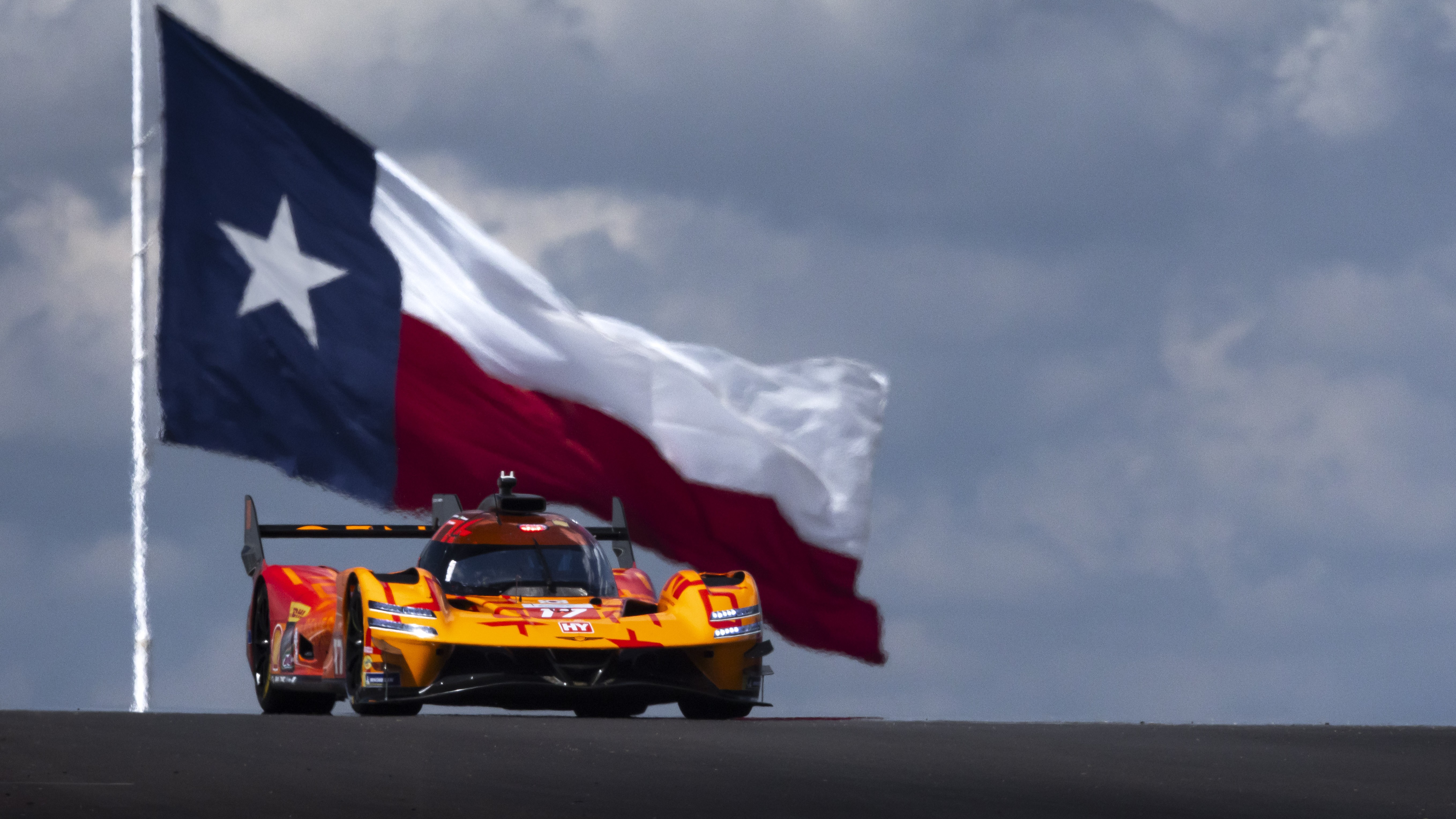 Genesis GMR-001 Hypercar climbing a crest with the Texas flag behind