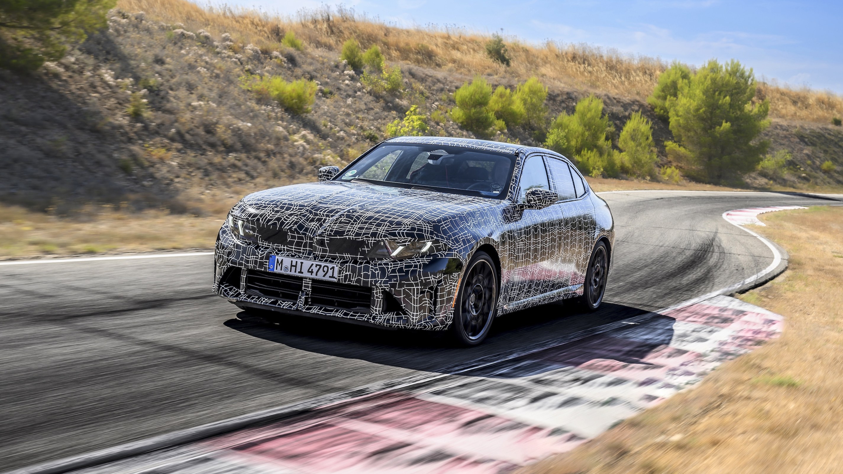 Camouflaged BMW M350 xDrive prototype cornering at Miramas test track