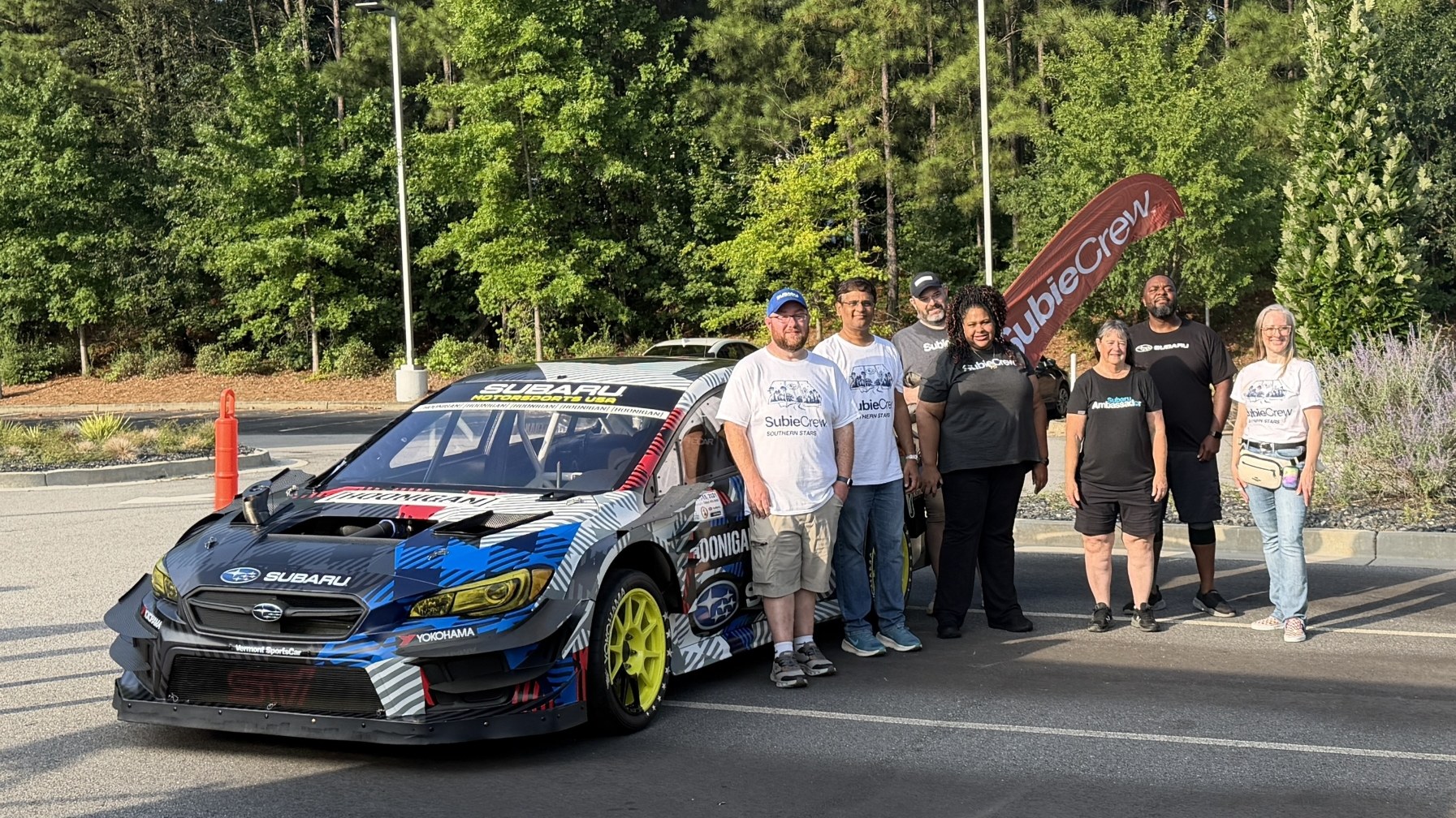 SubieCrew Southern Stars chapter members pose beside a Subaru Motorsports USA rally car