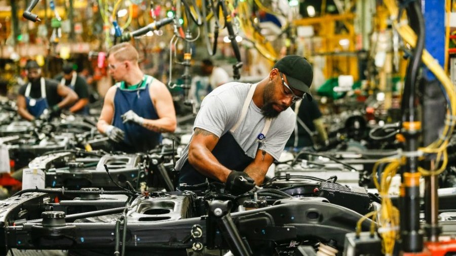Workers assemble vehicle chassis on a GM production line in Lansing