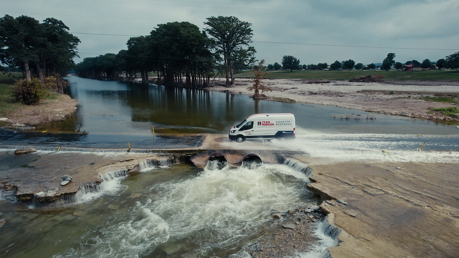 Team Rubicon Ford Transit crossing a flooded low-water crossing in Texas