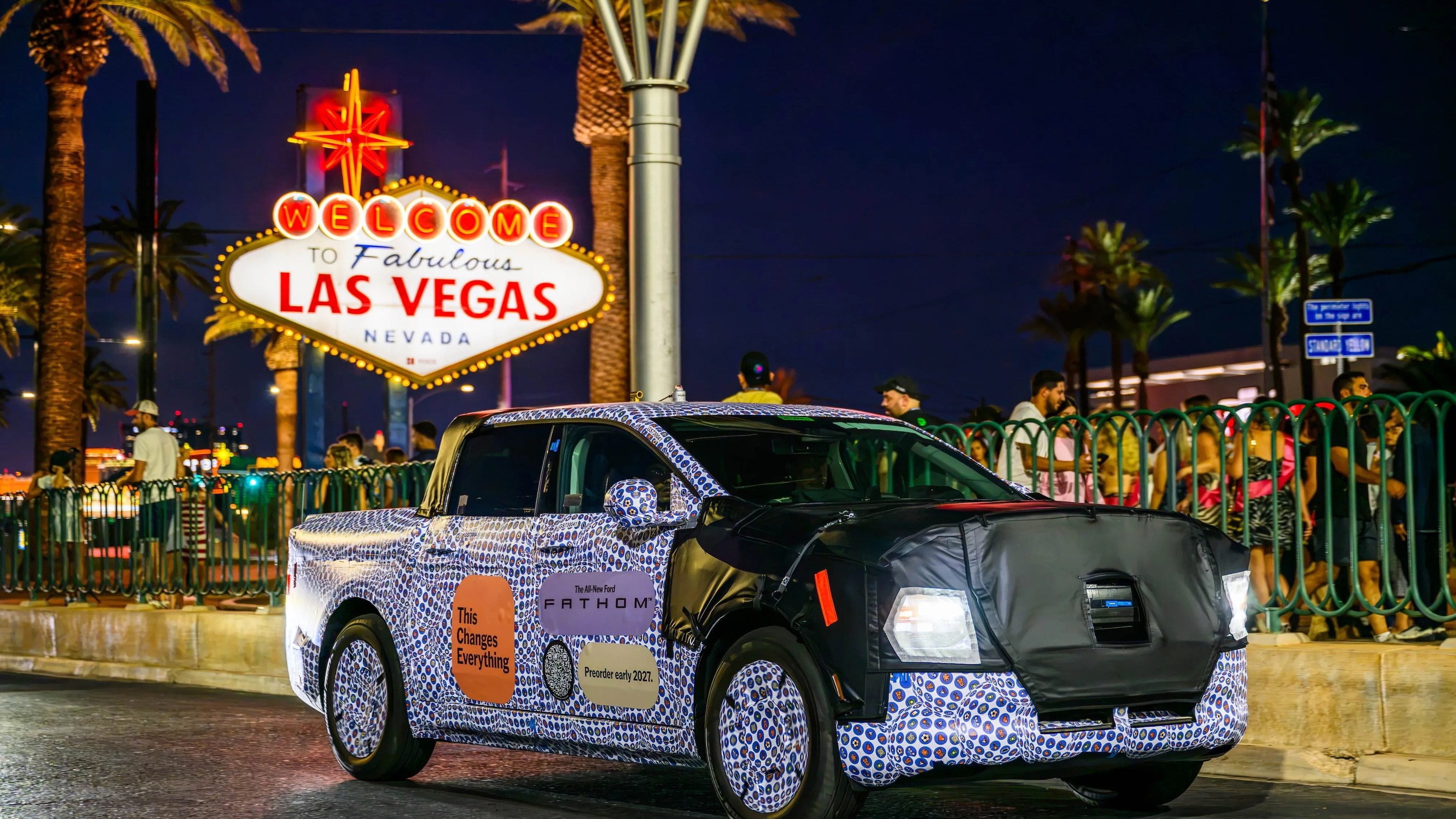 Camouflaged Ford Fathom electric truck prototype at the Welcome to Las Vegas sign at night