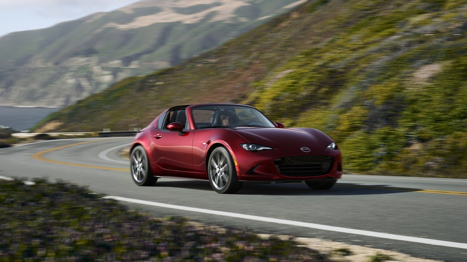 026 Mazda MX-5 Miata RF in Soul Red driving on a coastal highway