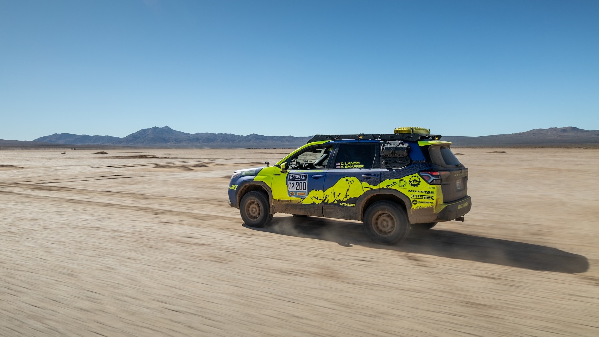 Subaru Forester Hybrid rally car driving across a dry desert lakebed