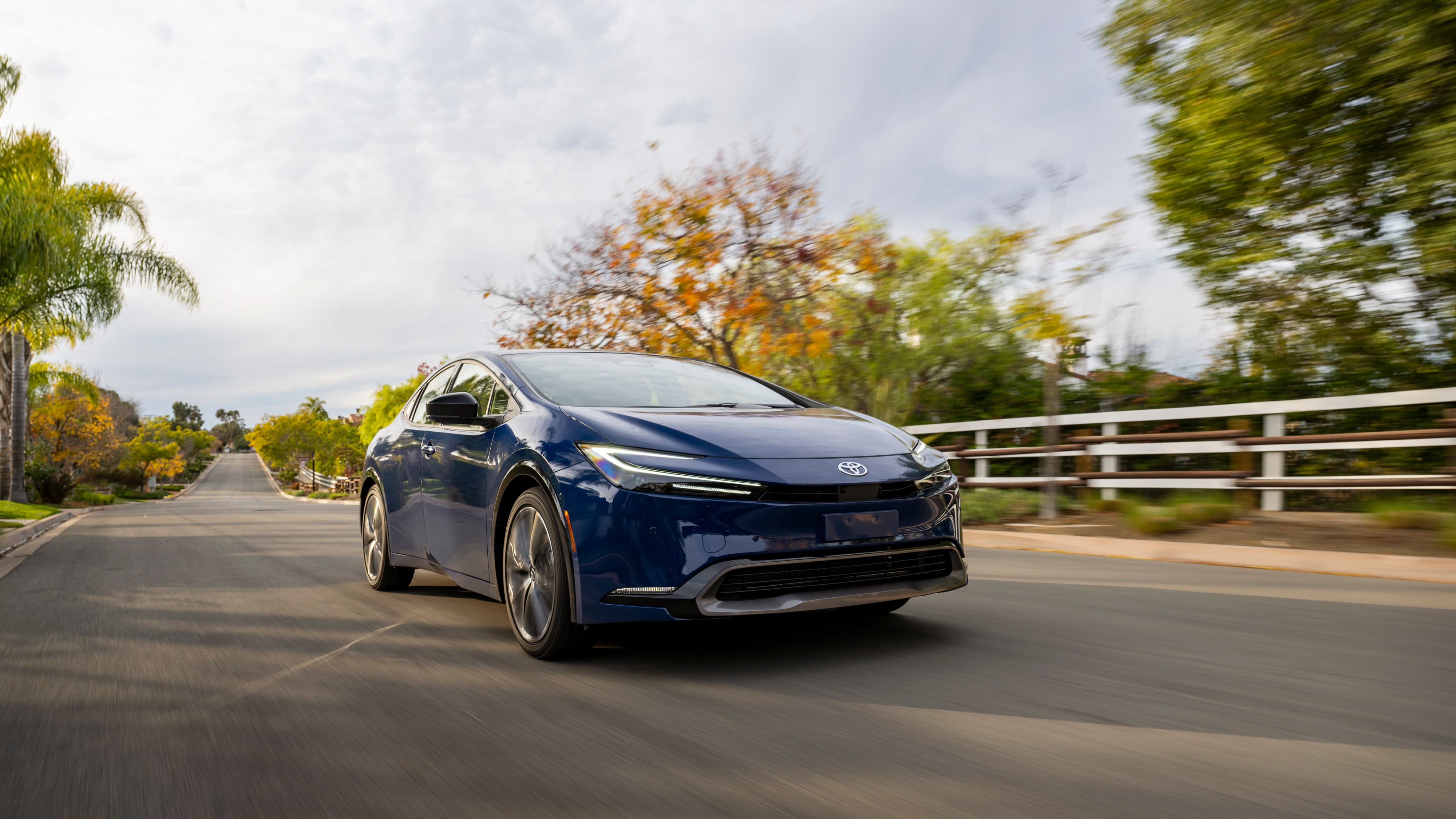 2026 Toyota Prius Limited in blue driving on a suburban road