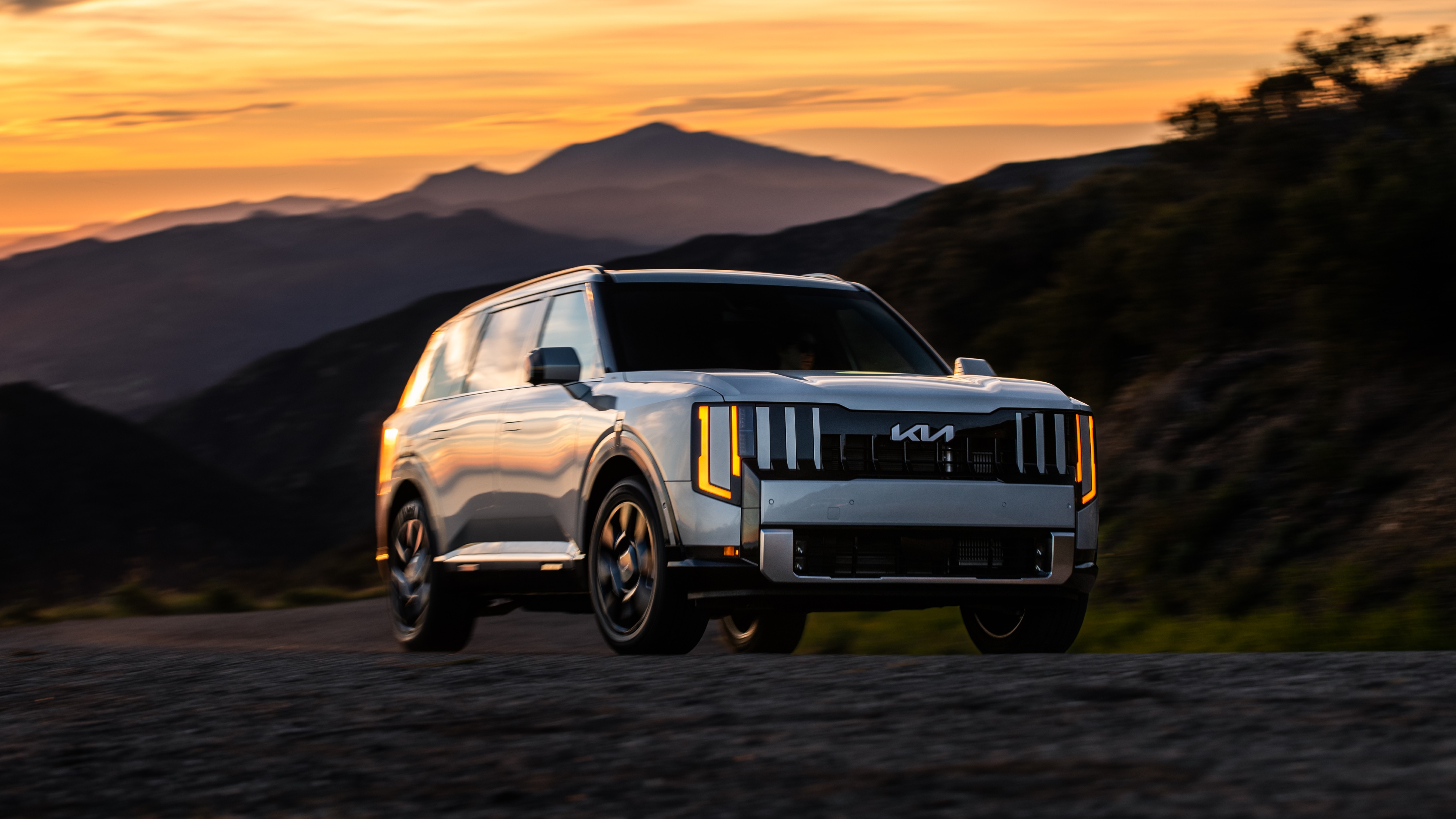 Silver 2027 Kia Telluride driving on a mountain road at sunset