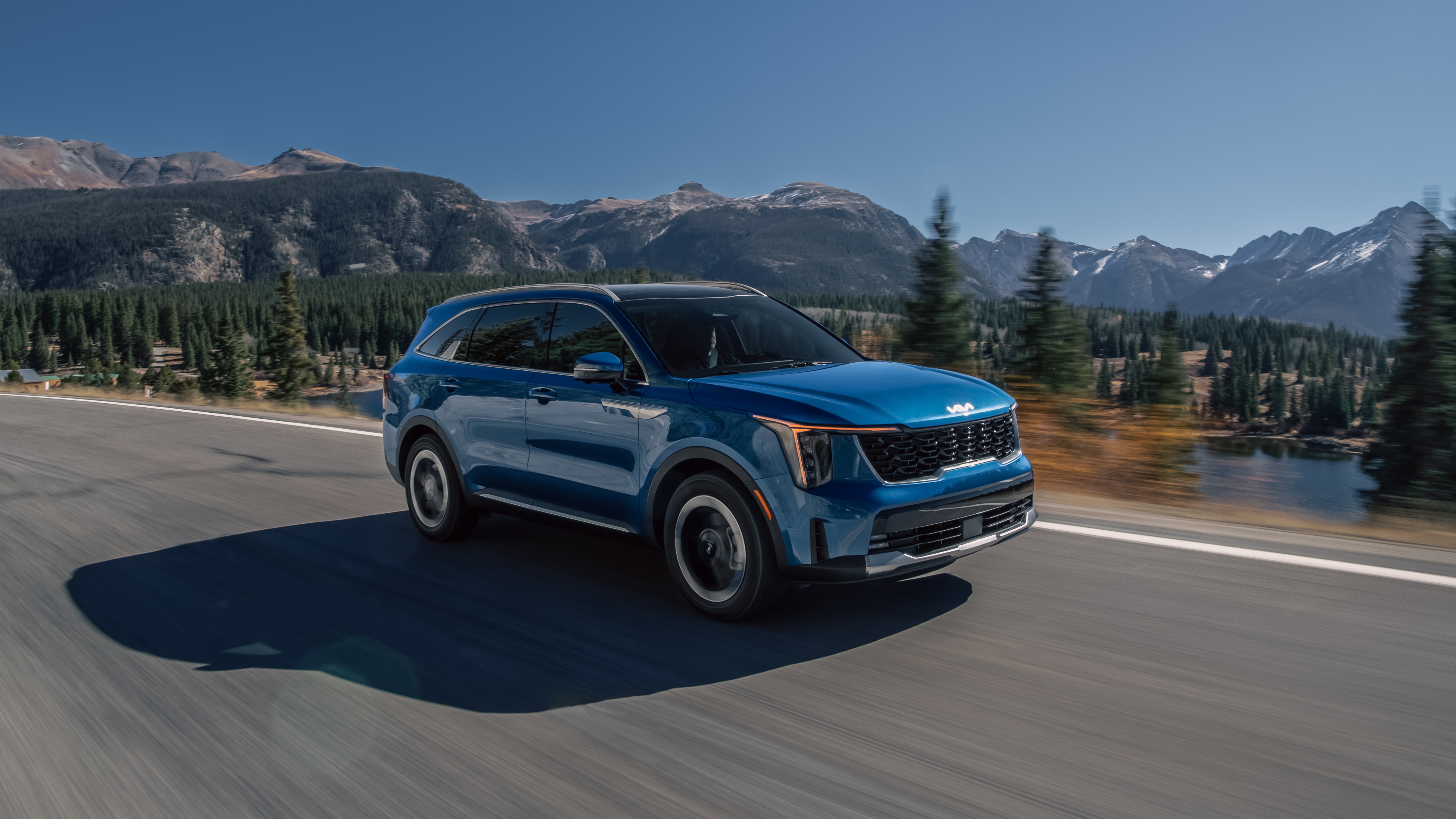 2027 Kia Sorento Hybrid in blue driving on a mountain road, front three-quarter view