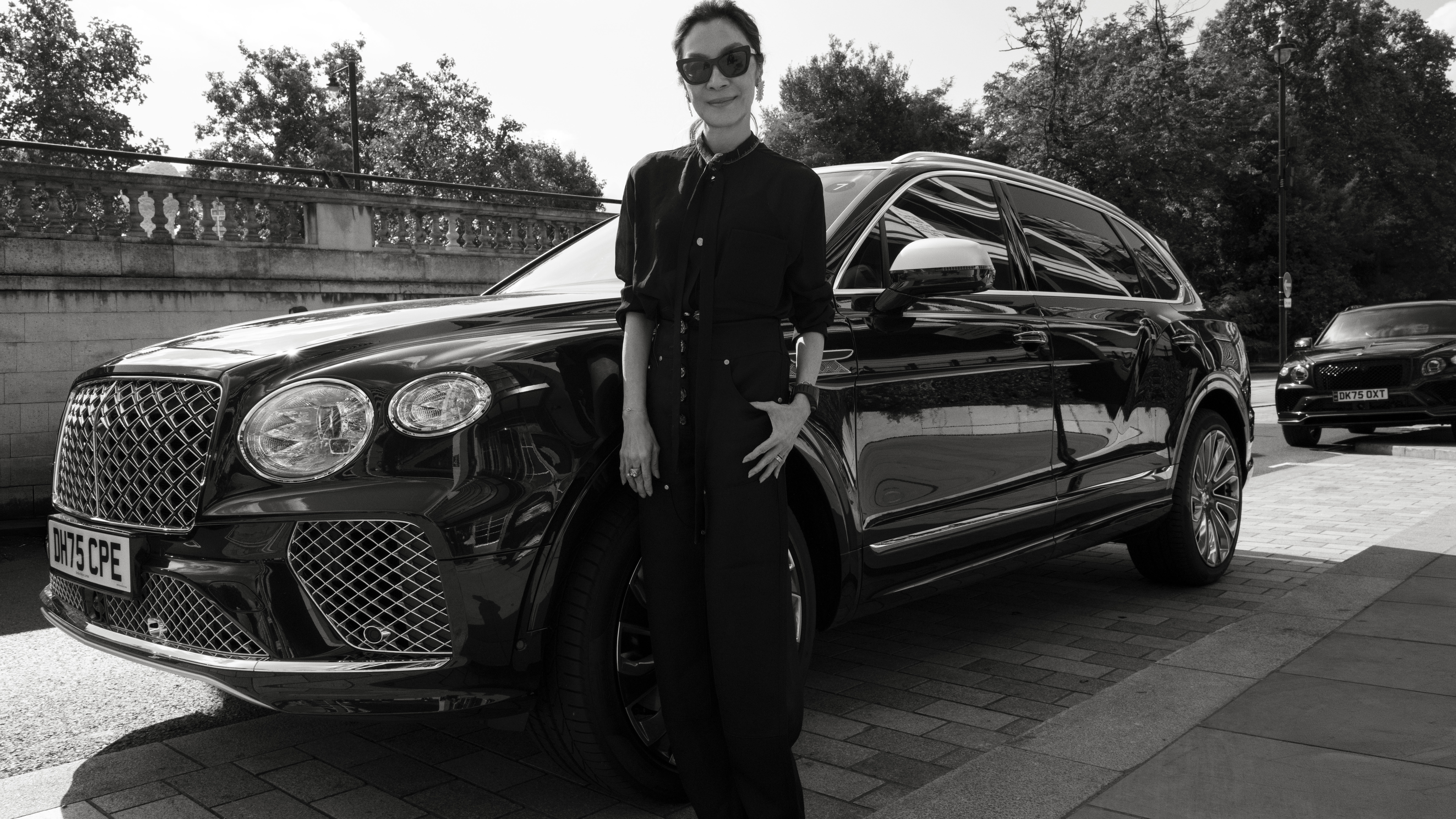 Michelle Yeoh standing beside a black Bentley Bentayga EWB in London