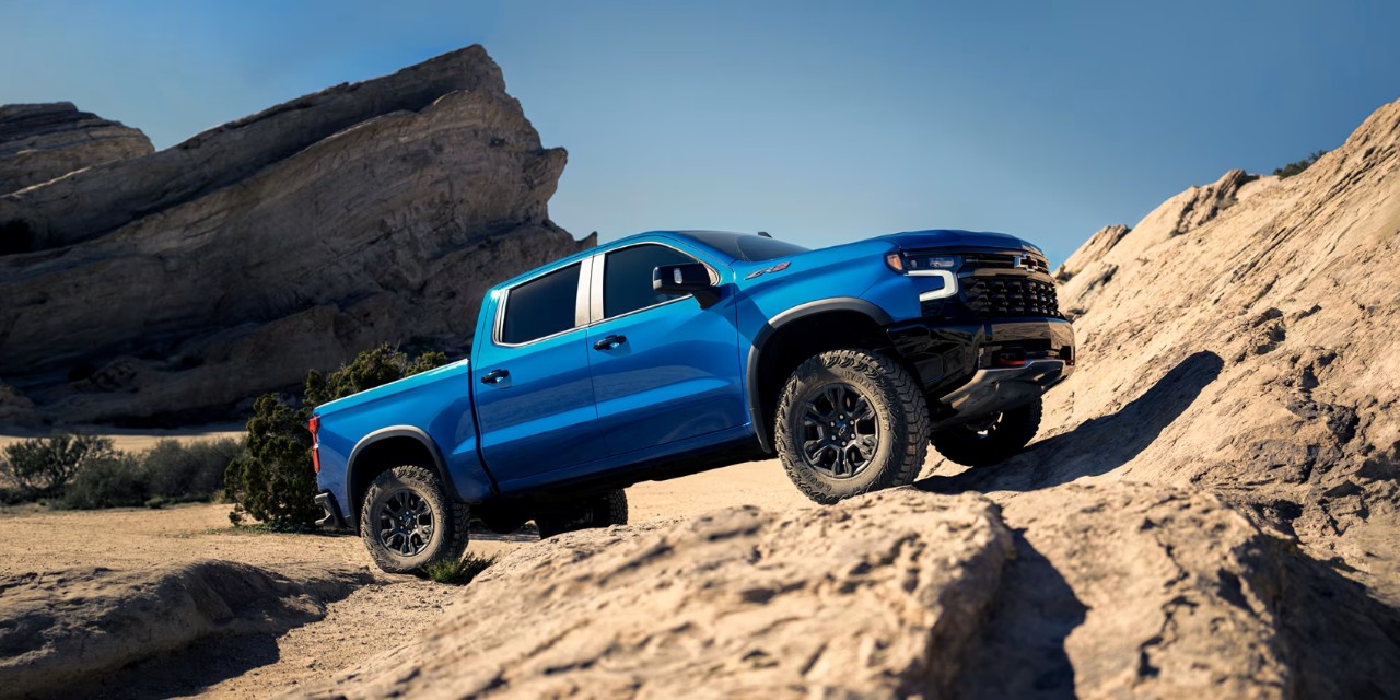 Blue Chevrolet Silverado ZR2 pickup climbing a desert rock outcrop