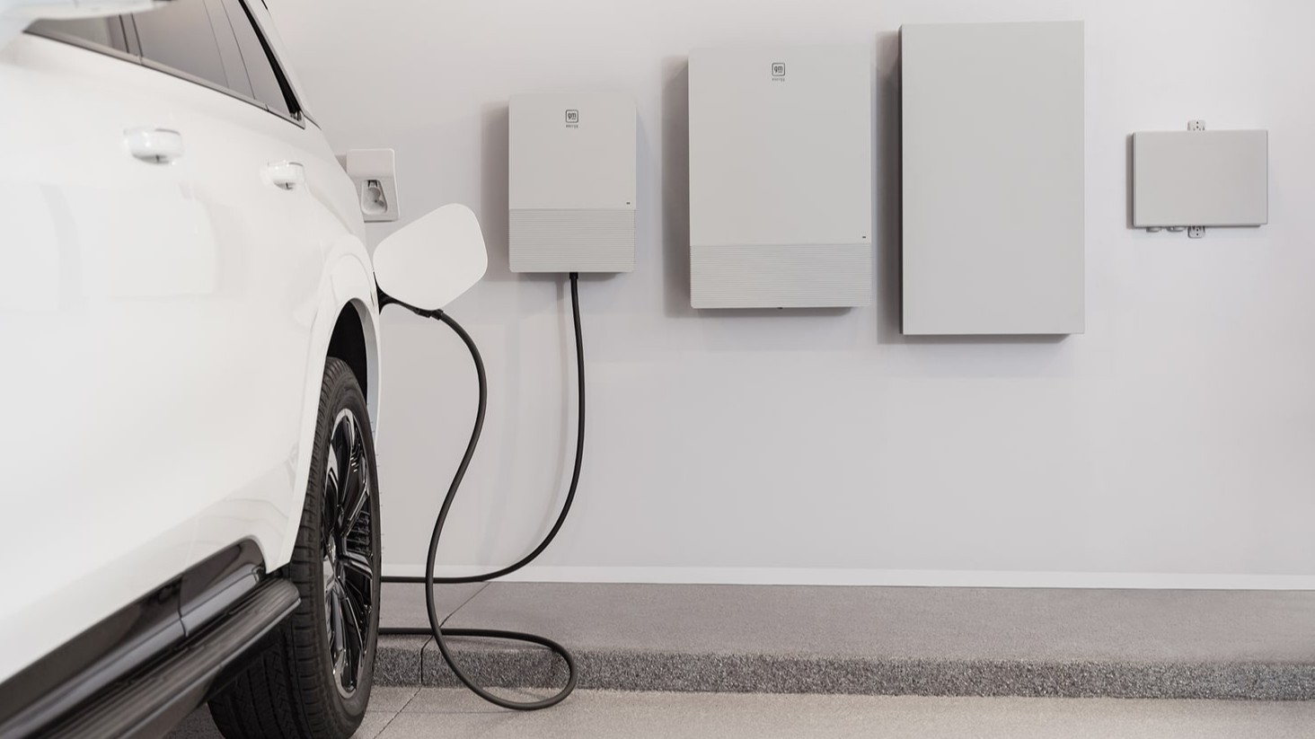 White GM electric vehicle plugged into GM Energy V2H hardware in a garage