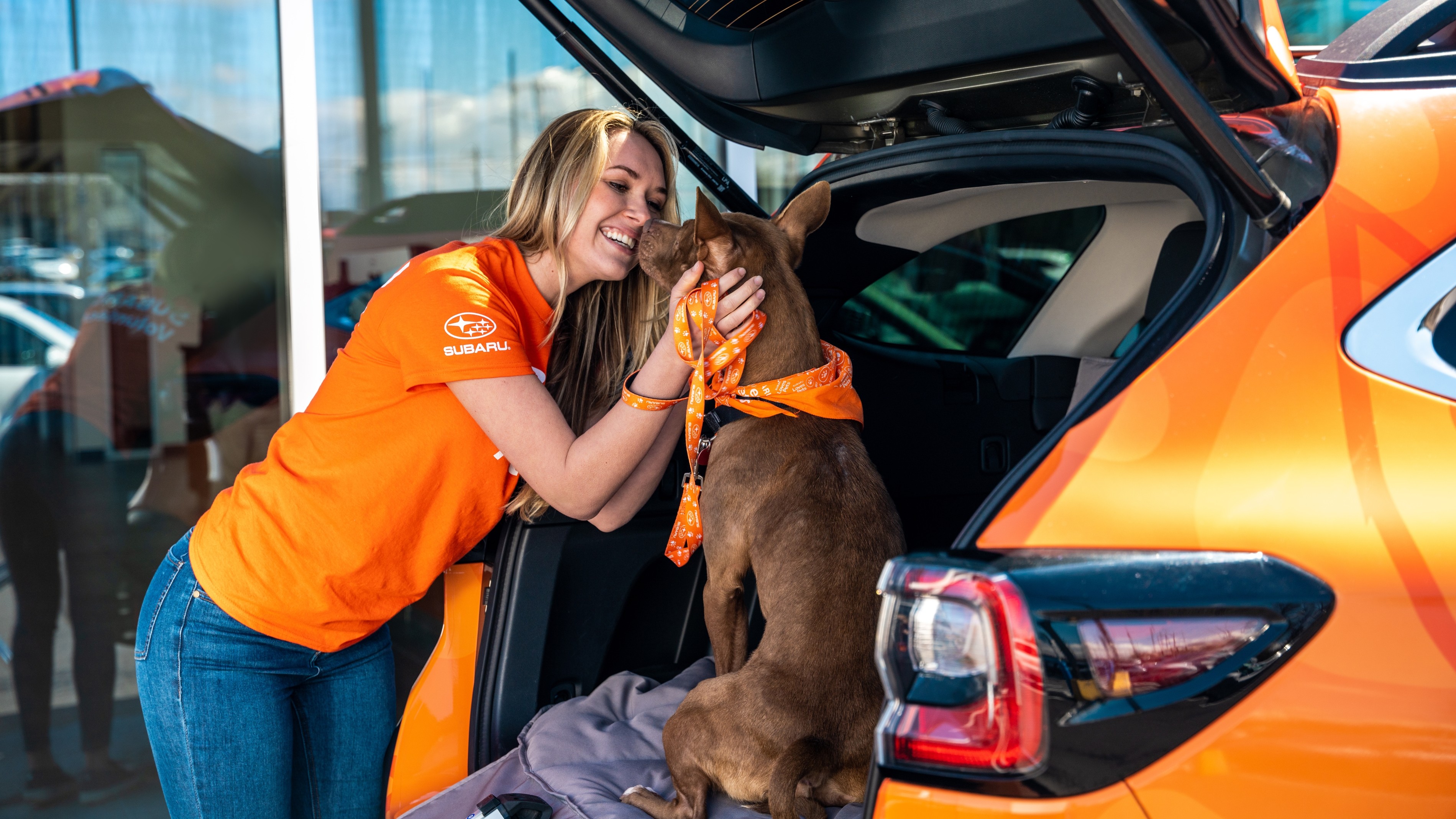 Subaru volunteer hugging a shelter dog in the open cargo area of a Crosstrek