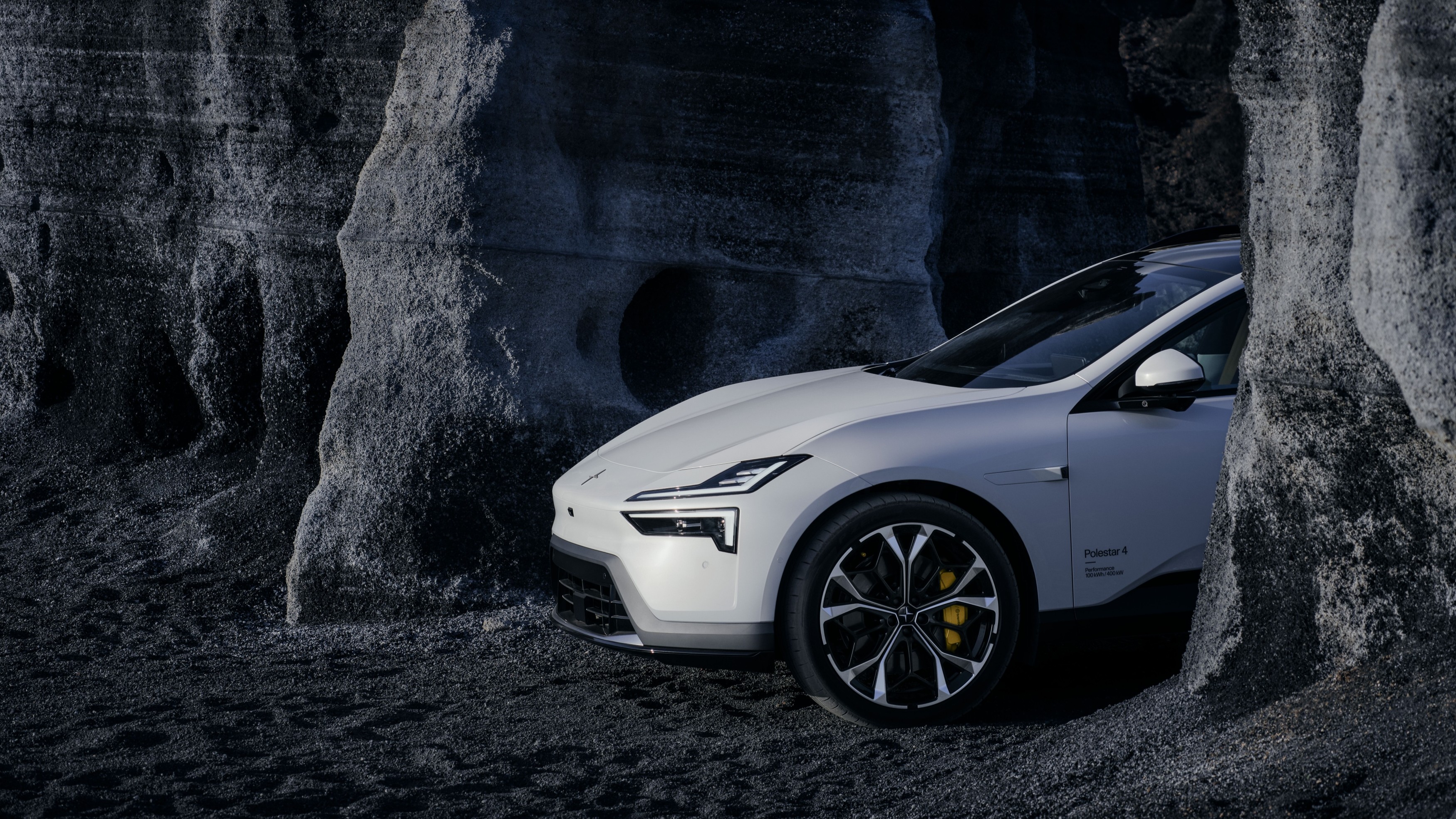 White Polestar 4 parked between dark volcanic rock formations