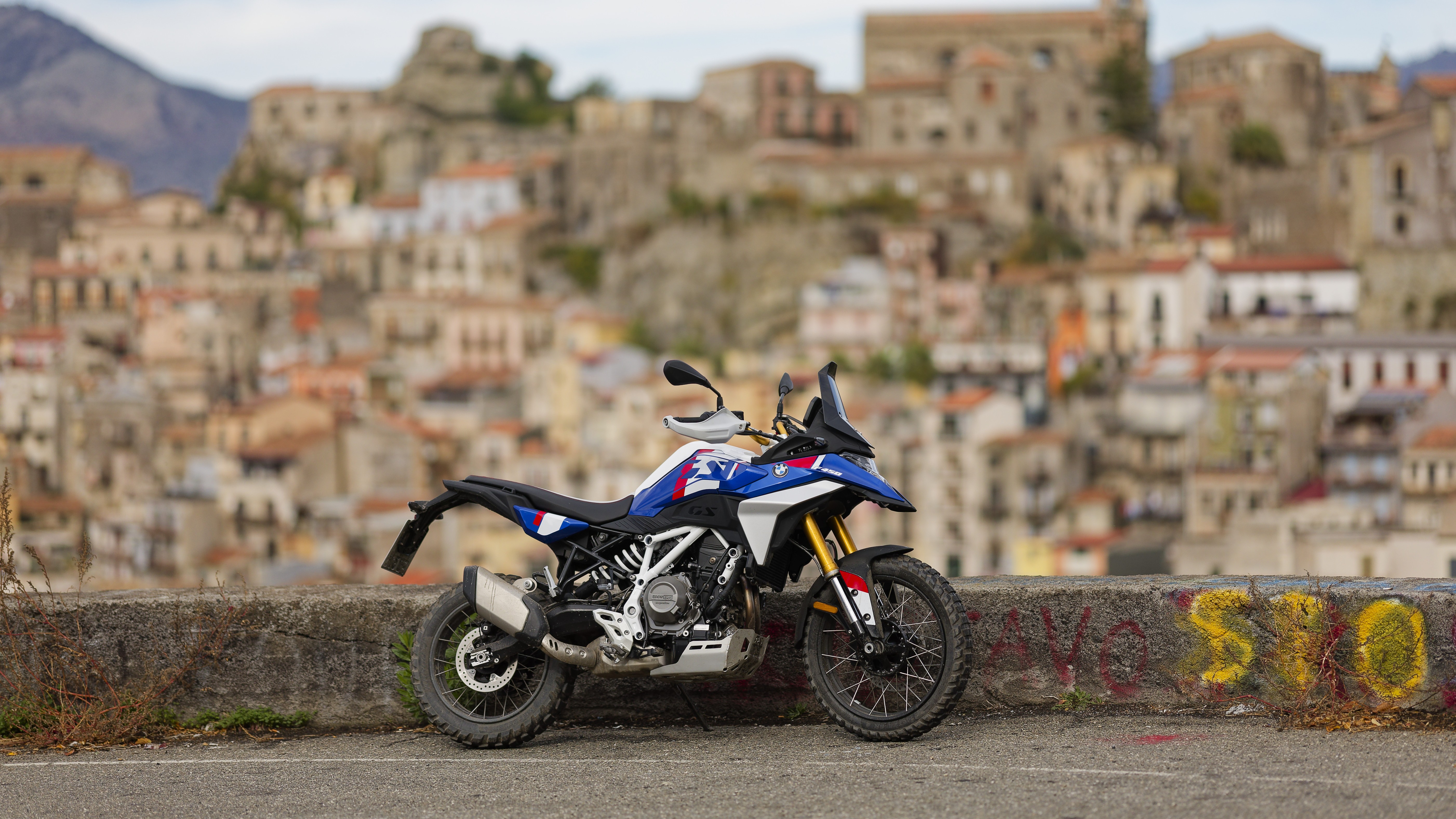 BMW F 450 GS GS Trophy parked in profile below a hilltop town