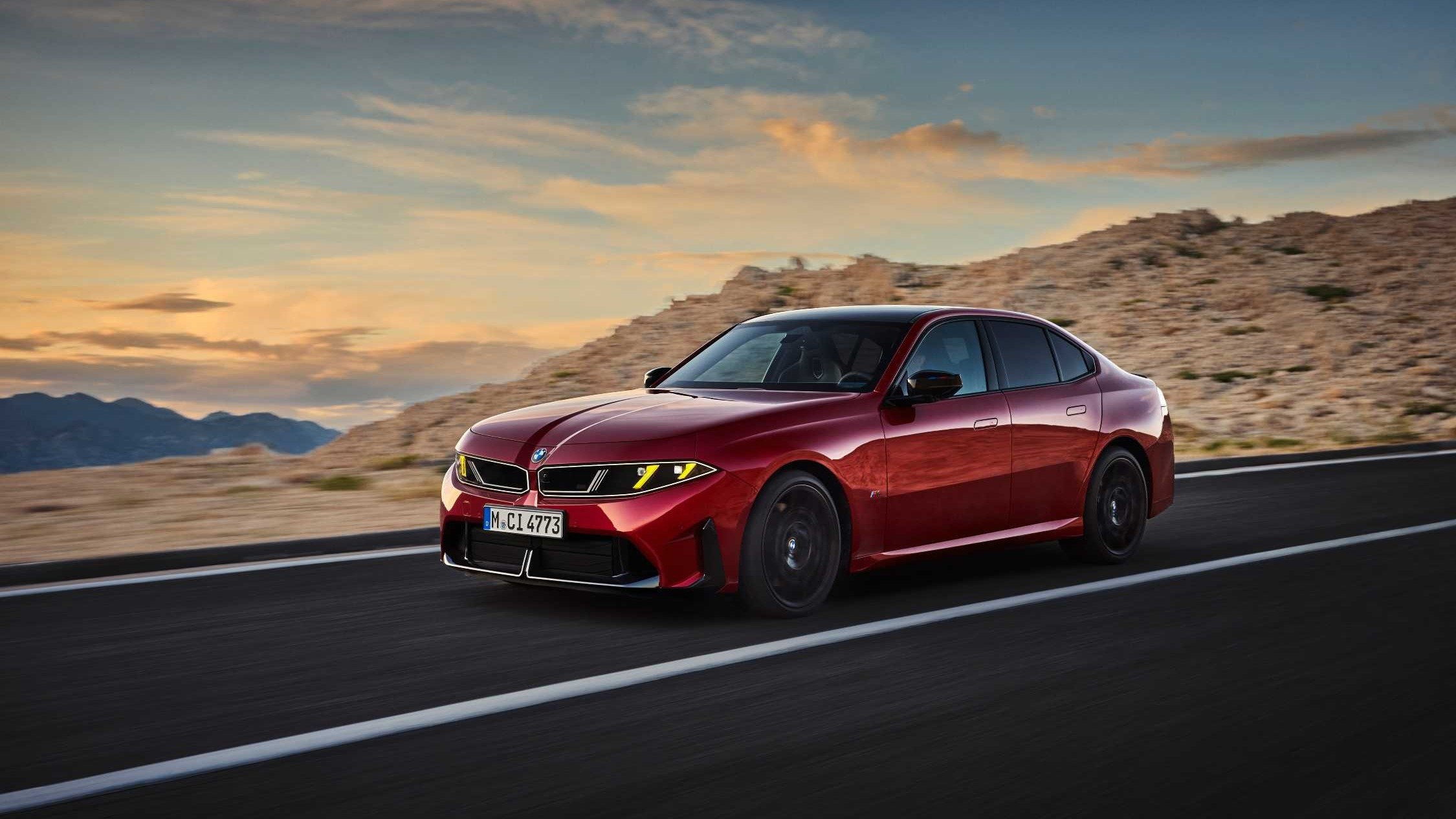 Red 2027 BMW M350 xDrive sedan driving on a desert road at sunset