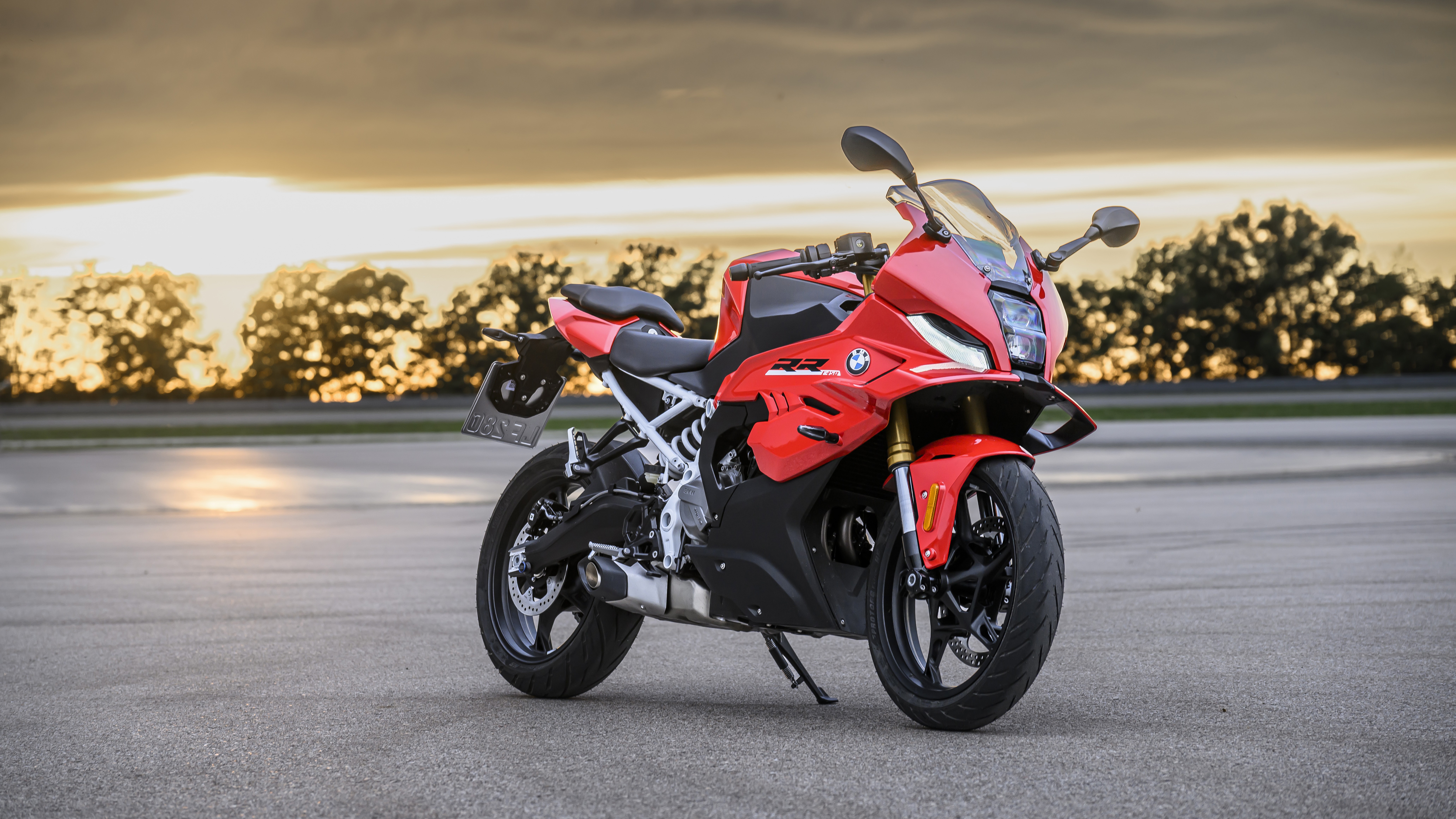 Red BMW F 450 RR parked on a track apron at sunset, front three-quarter view