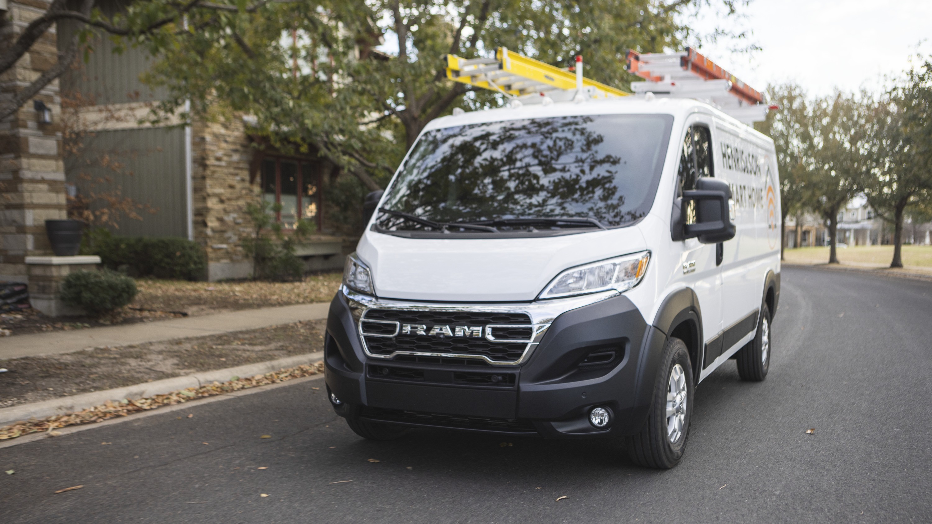 White Ram ProMaster cargo van with ladders on the roof, front three-quarter view