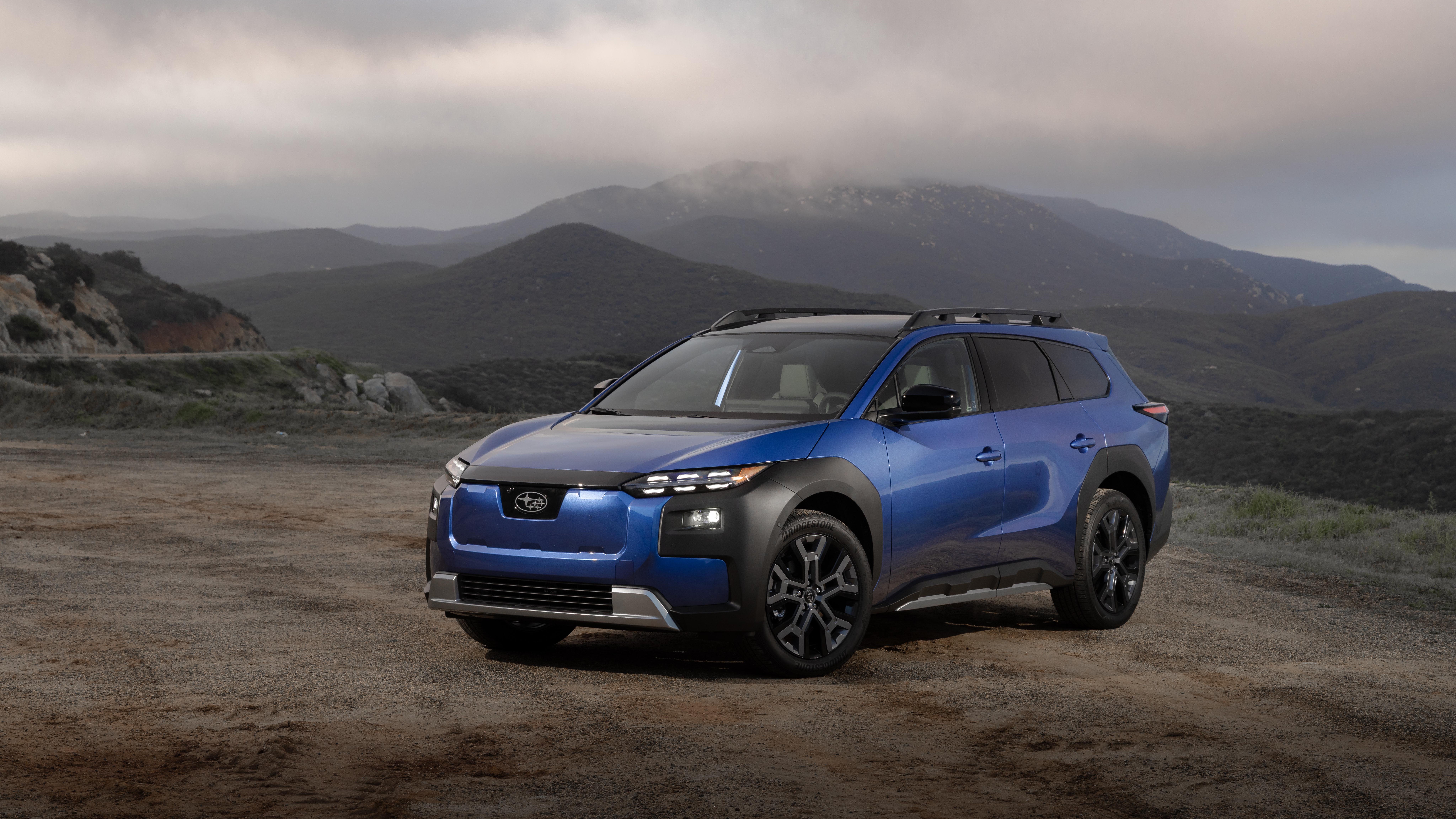 Blue Subaru Trailseeker electric SUV parked on a dirt overlook with mountains behind