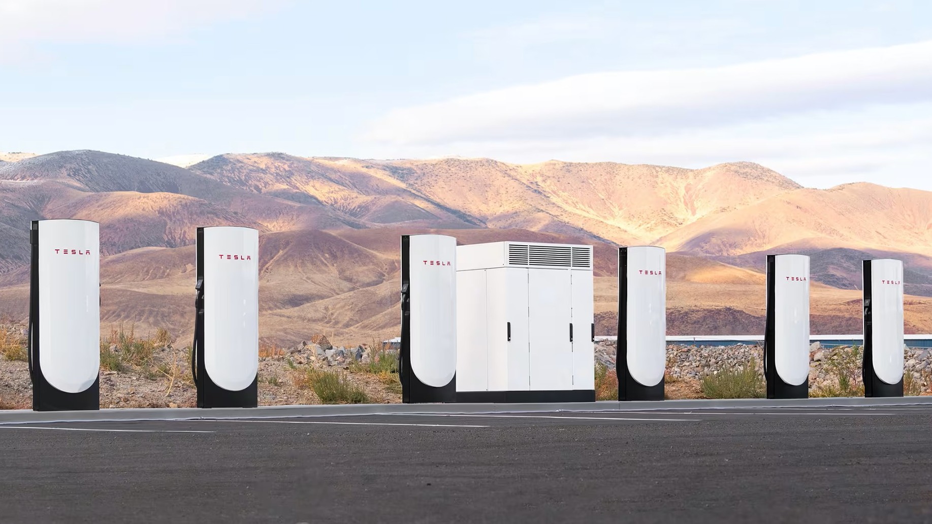 Row of Tesla Supercharger stalls with desert hills behind