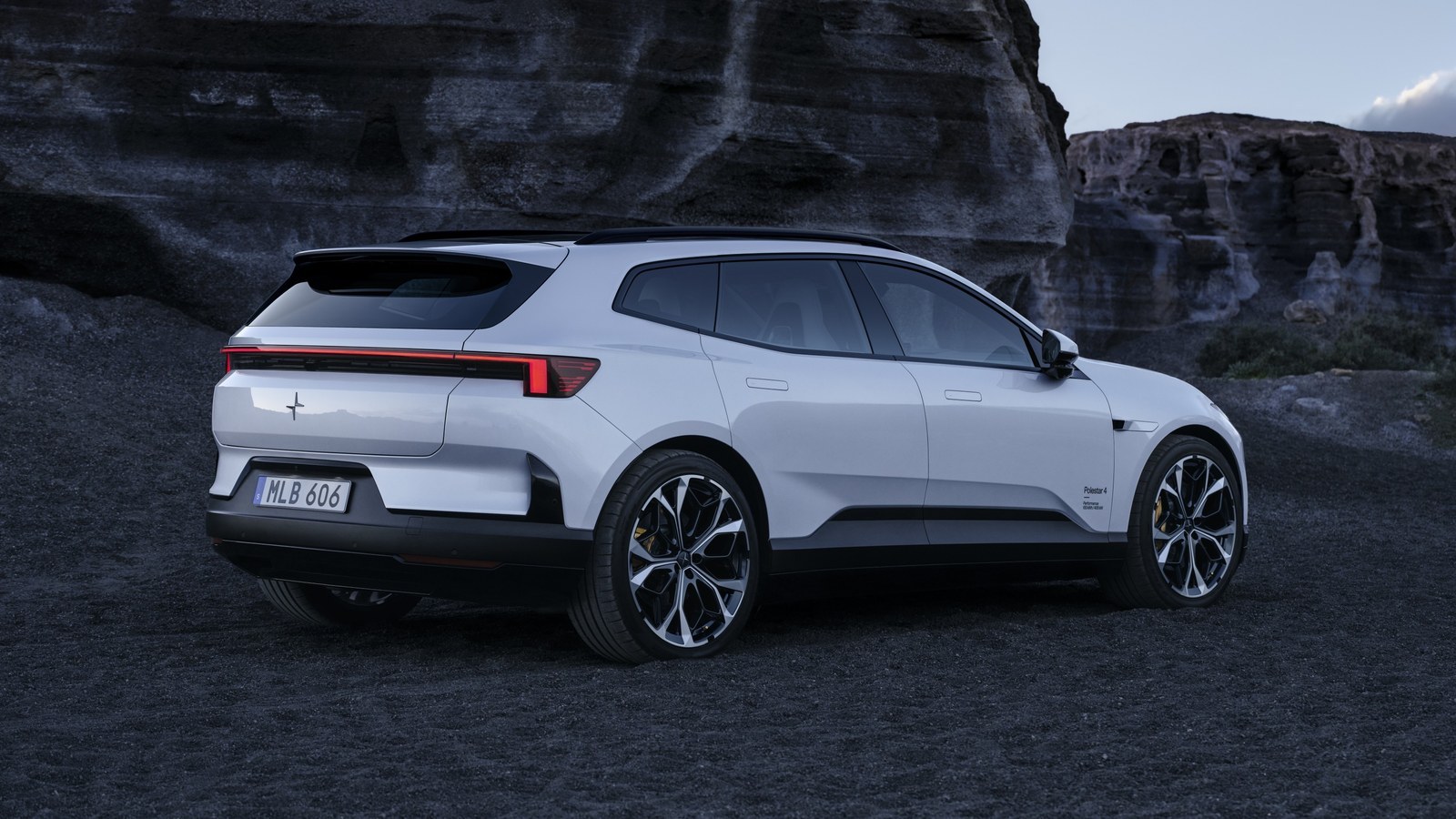 White Polestar 4 SUV with rear window parked by dark rock face
