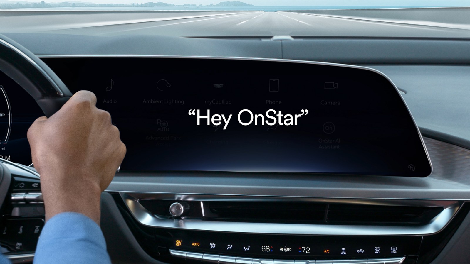 Driver's hand on wheel beside a GM touchscreen showing Hey OnStar prompt