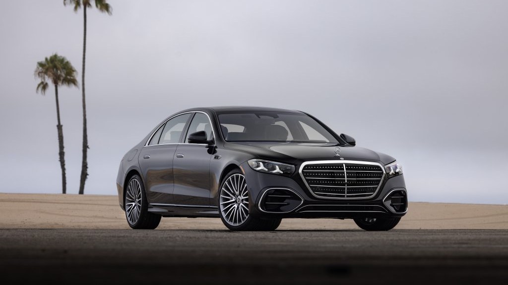 Black 2027 Mercedes-Benz S-Class sedan parked on a beach with palm trees