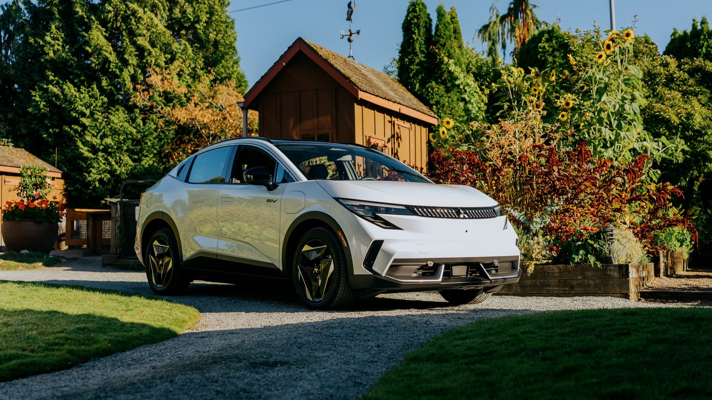 White 2027 Mitsubishi Eclipse Sportback EV parked on a gravel driveway