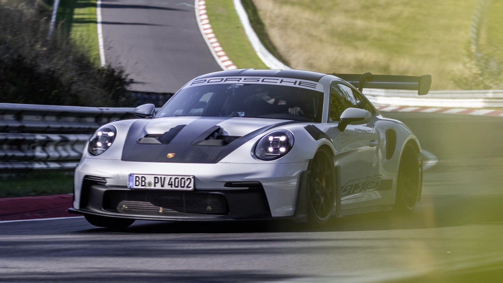 Silver Porsche 911 GT3 RS cornering on a race track