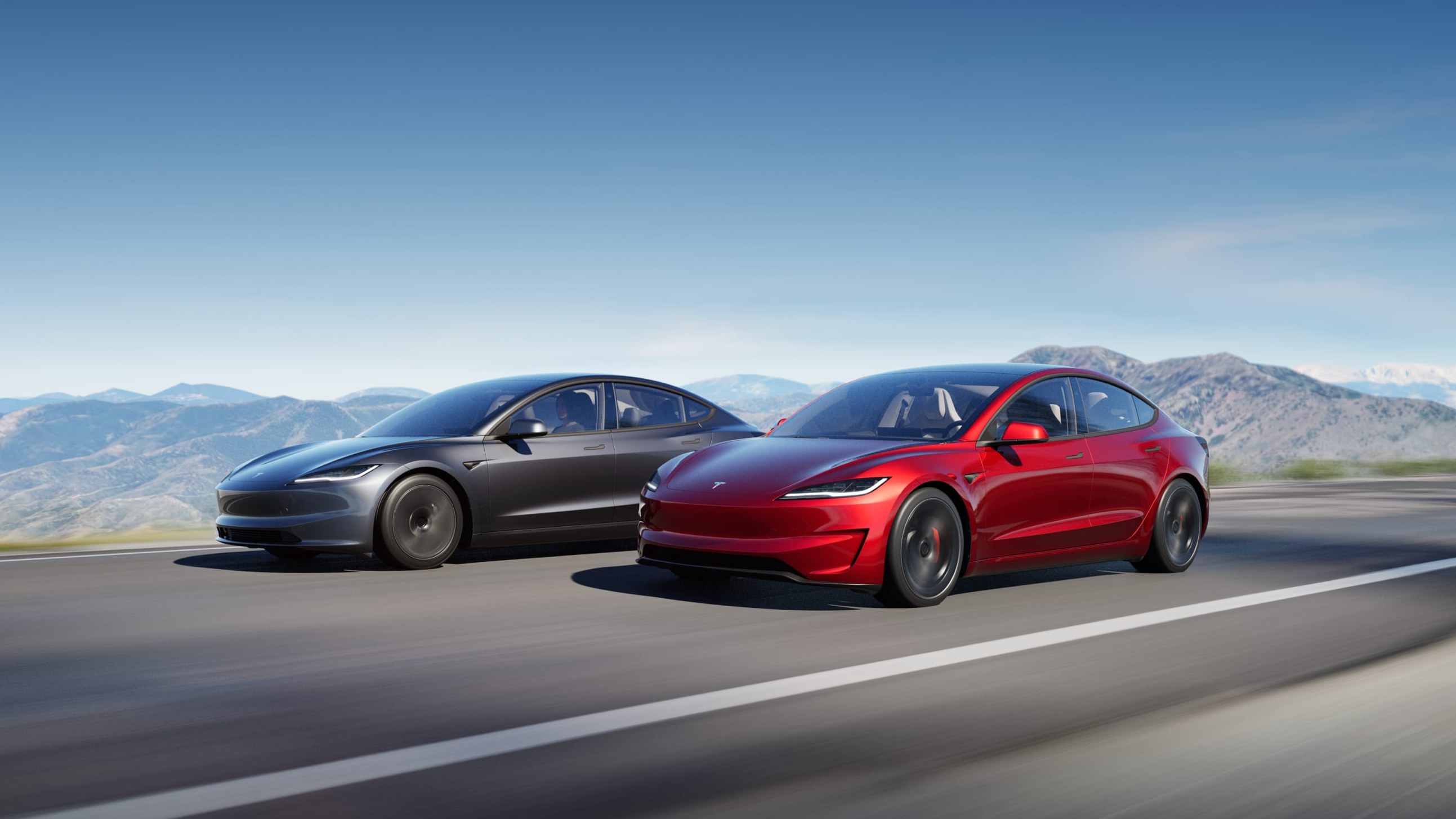 Two Tesla Model 3 sedans driving on a mountain road
