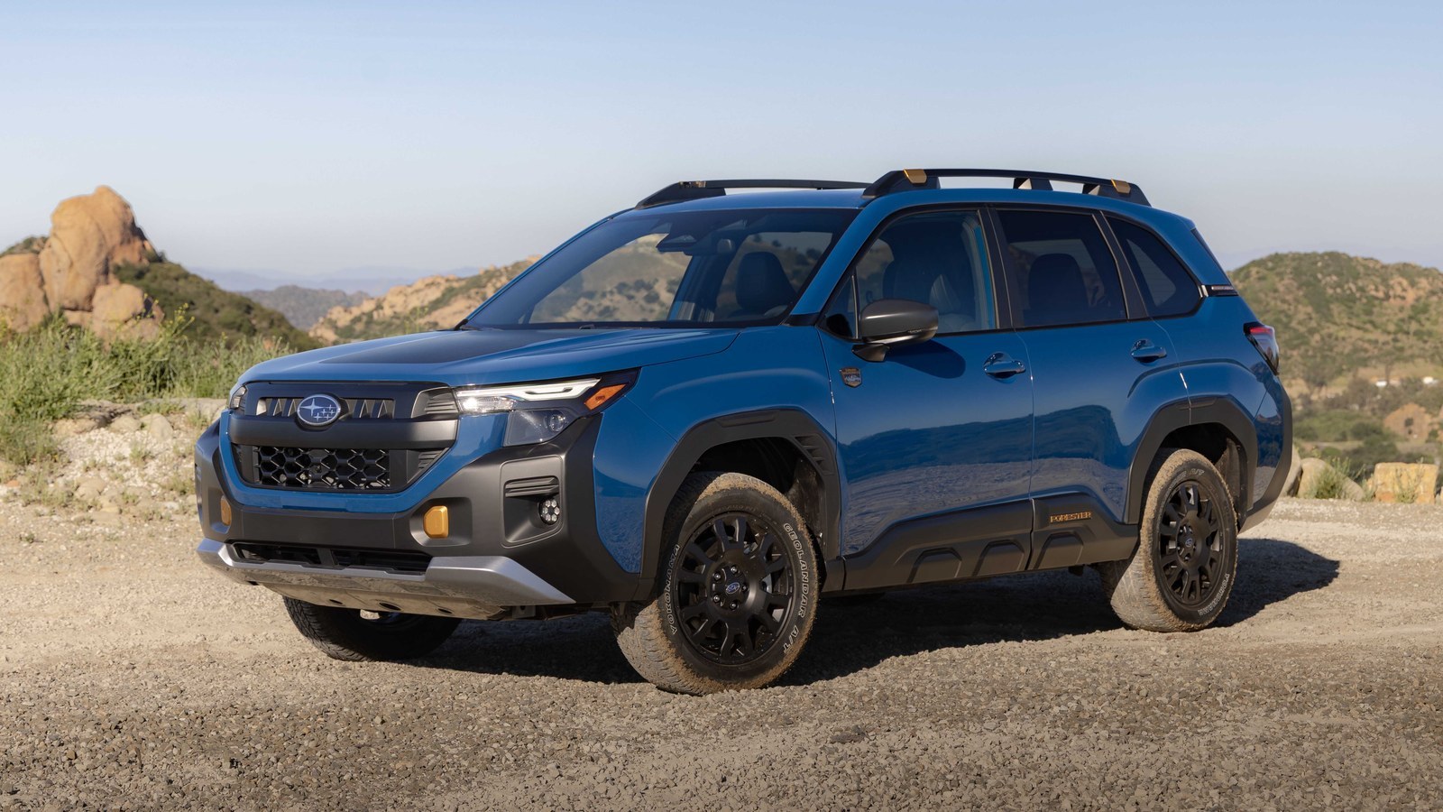 Blue 2027 Subaru Forester Wilderness Hybrid parked on a gravel overlook