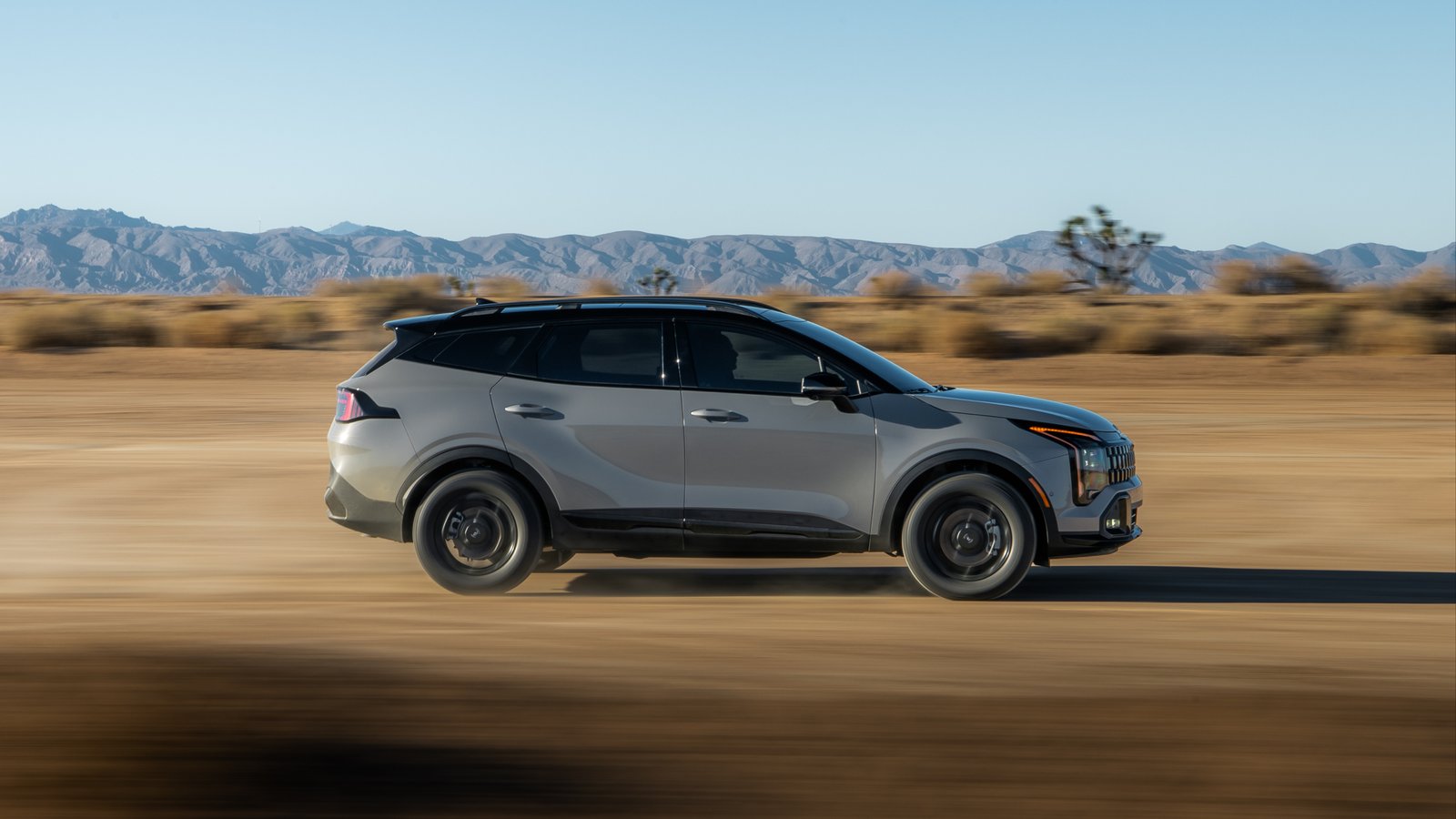 Side profile of 2027 Kia Sportage X-Line at speed in the desert