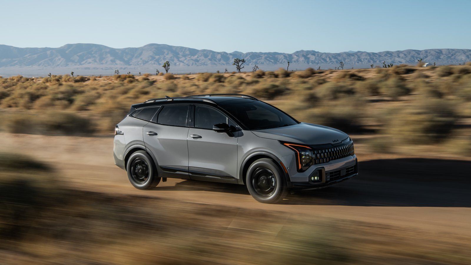 2027 Kia Sportage X-Line driving on a desert dirt road, front three-quarter view