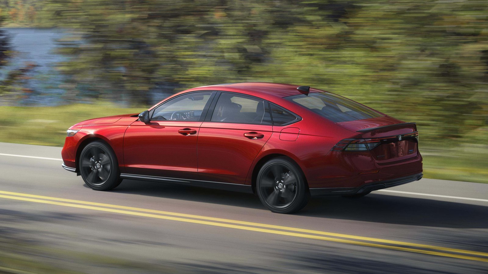 2026 Honda Accord Sport-L Hybrid driving on a lakeside road, rear three-quarter view