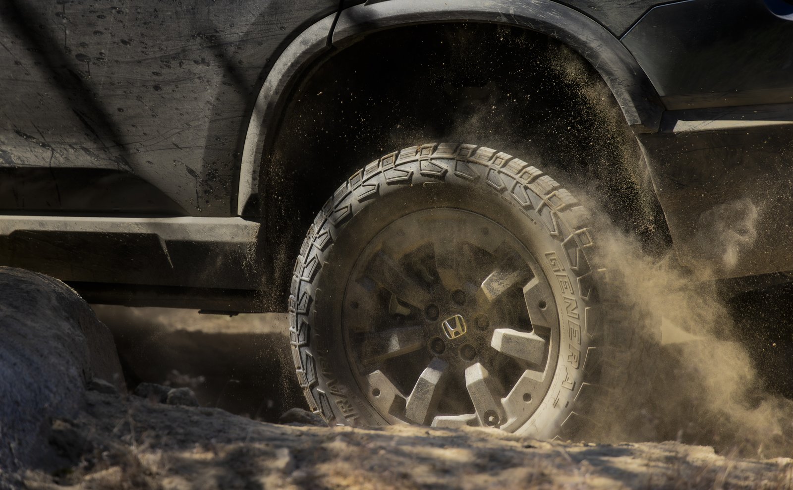 Honda Passport TrailSport all-terrain tire kicking up dirt under a wheel arch