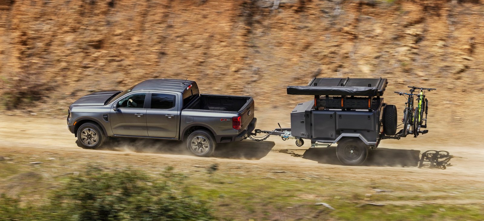 Ford Ranger Lariat FX4 towing an off-road camping trailer on a dirt road